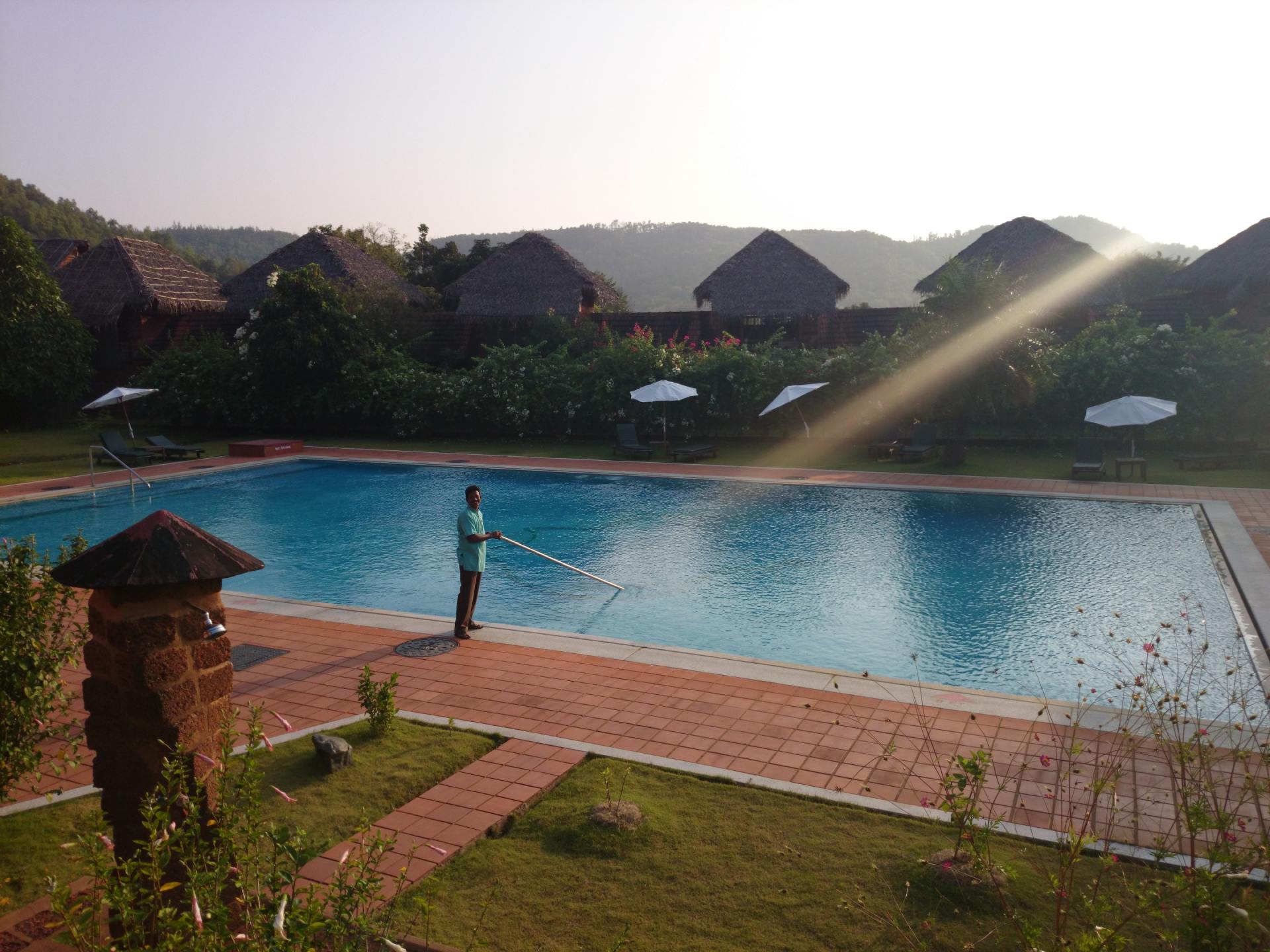 A man is cleaning a swimming pool with a hose