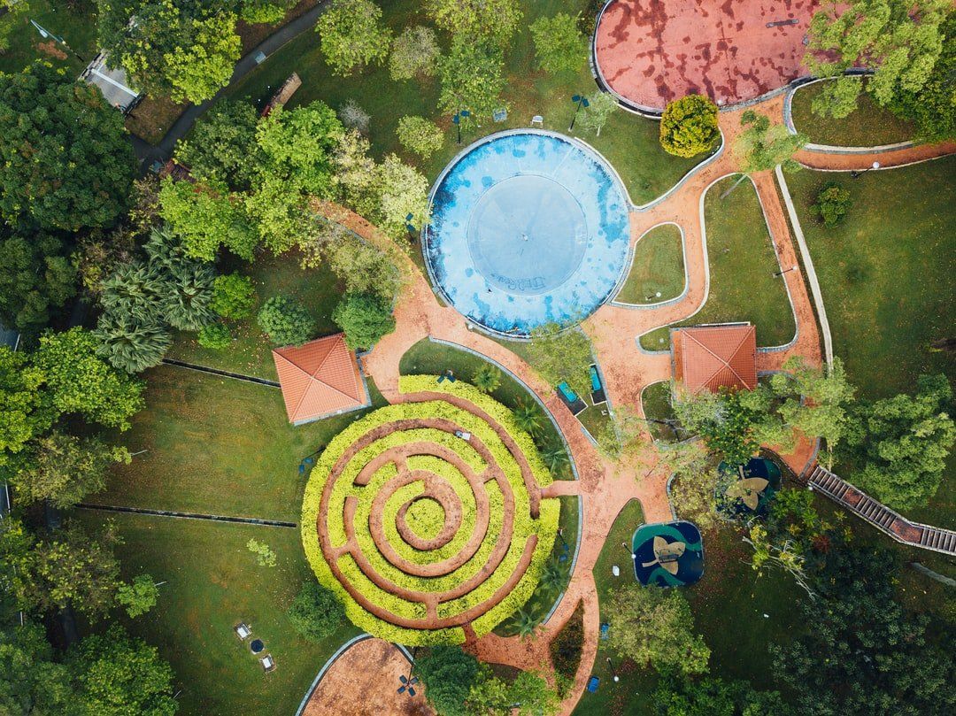 An aerial view of a park with a maze and a pool.