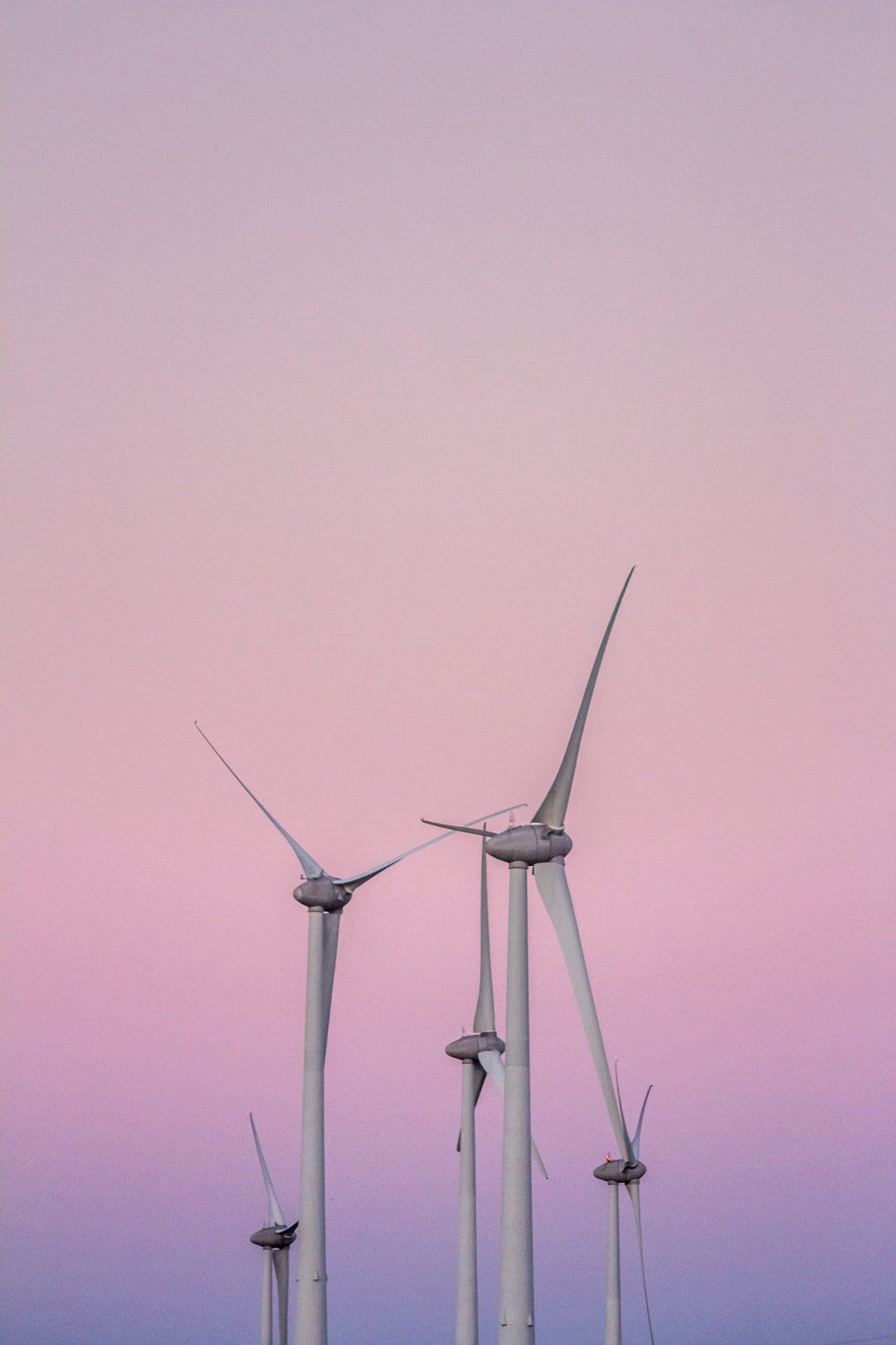 Wind turbines silhouetted against a pink and purple dusk sky