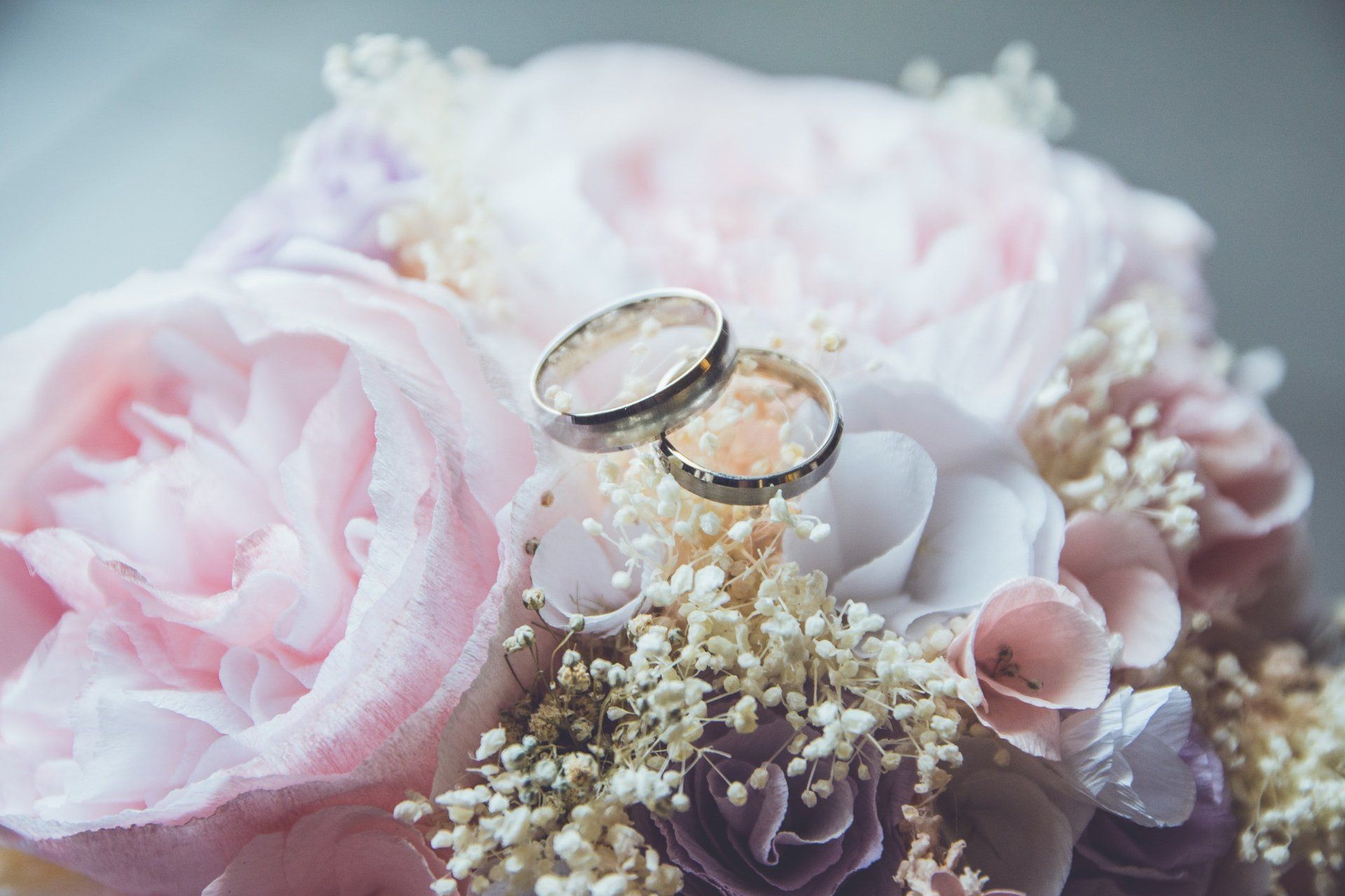 A couple of wedding rings sitting on top of a bouquet of flowers.