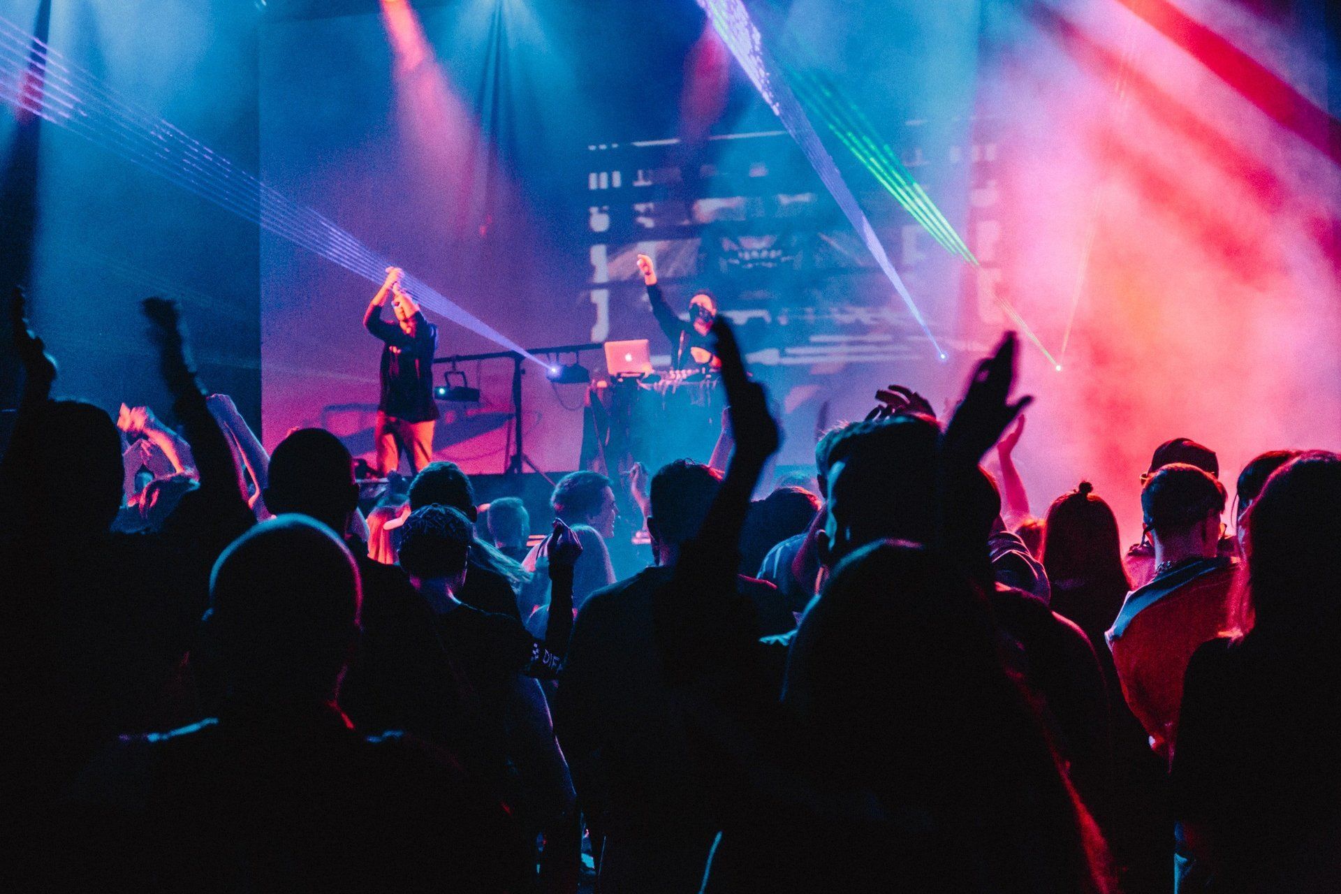 A crowd of people are standing in front of a stage at a concert.