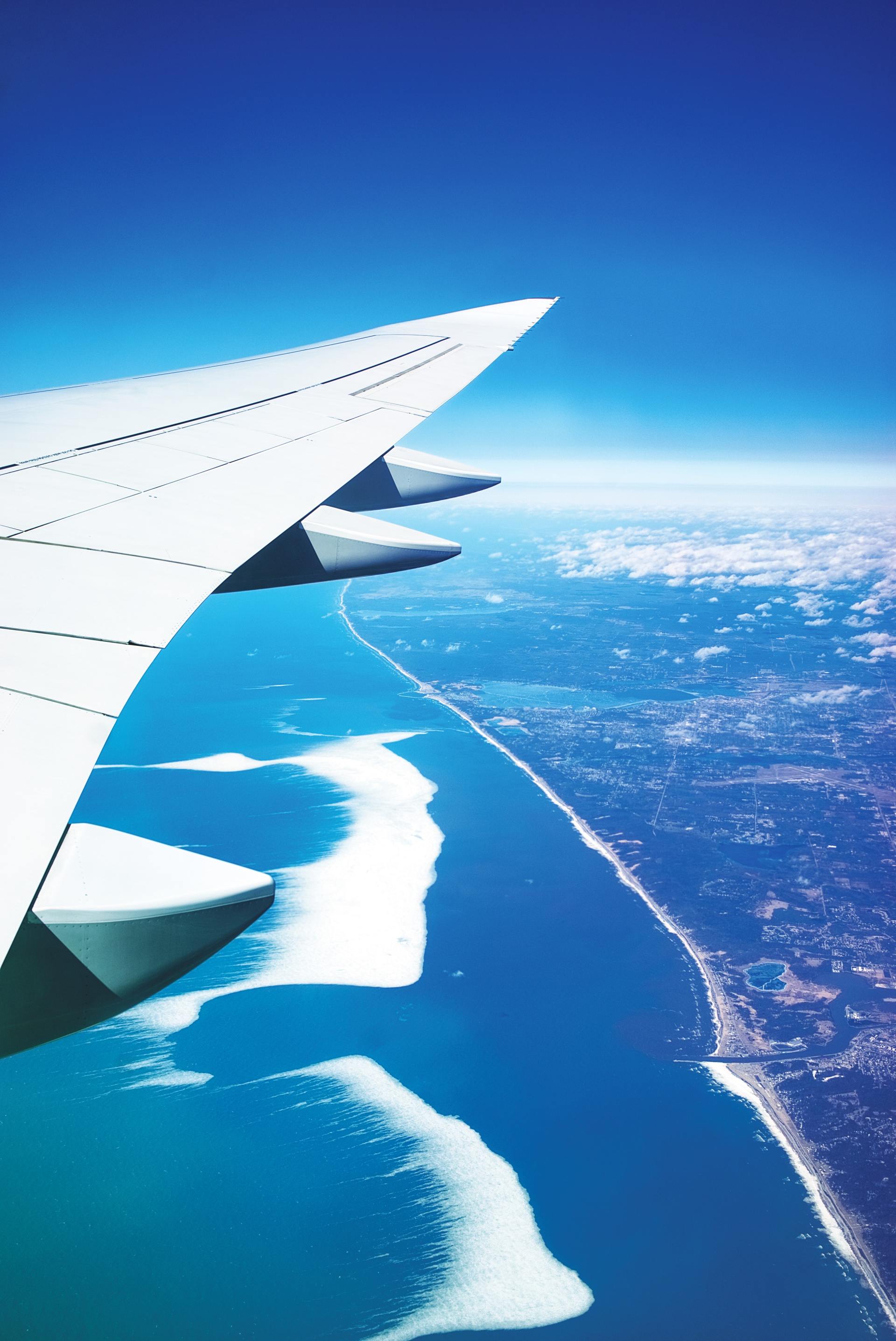 An airplane wing is flying over a body of water