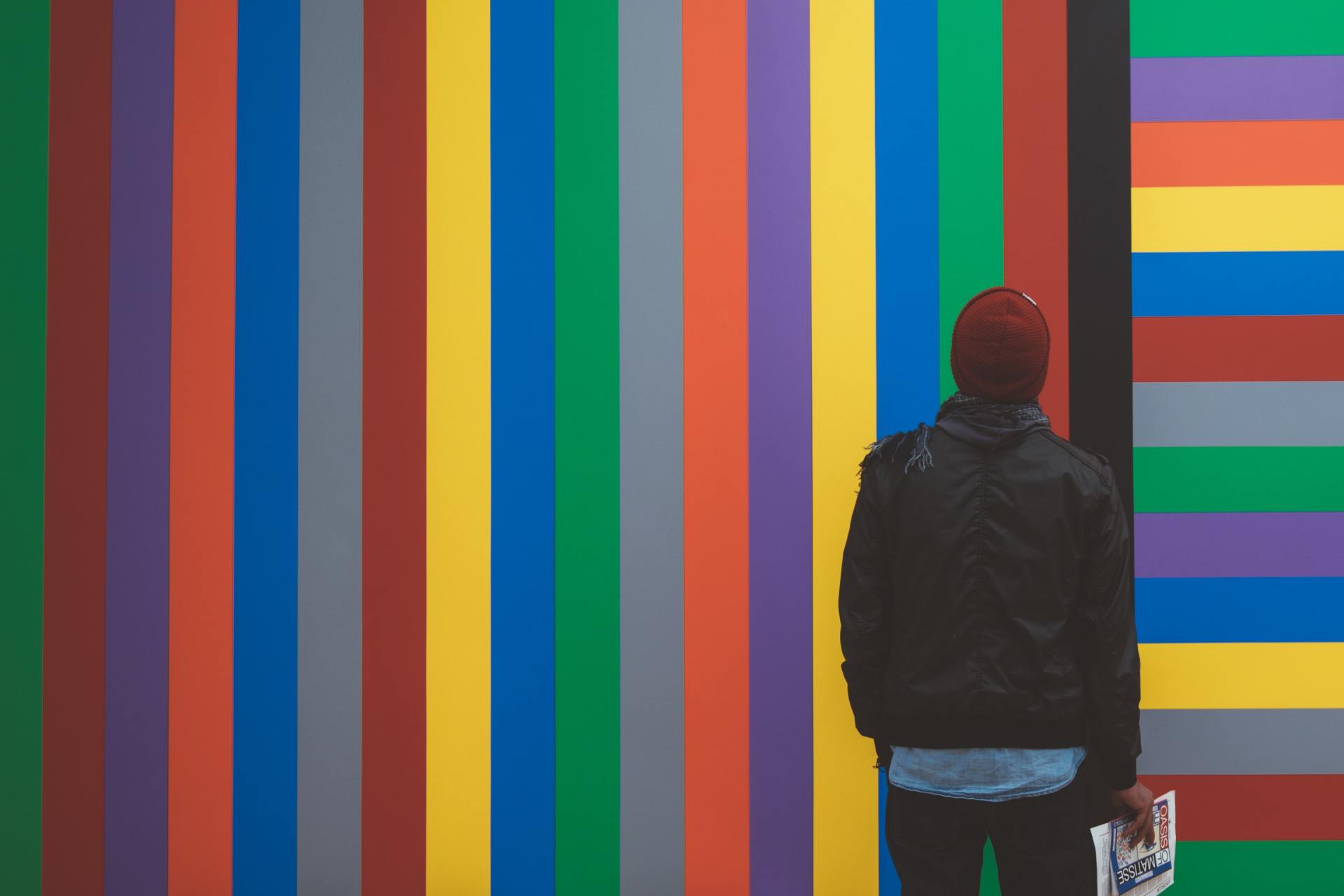 A man is standing in front of a colorful striped wall.