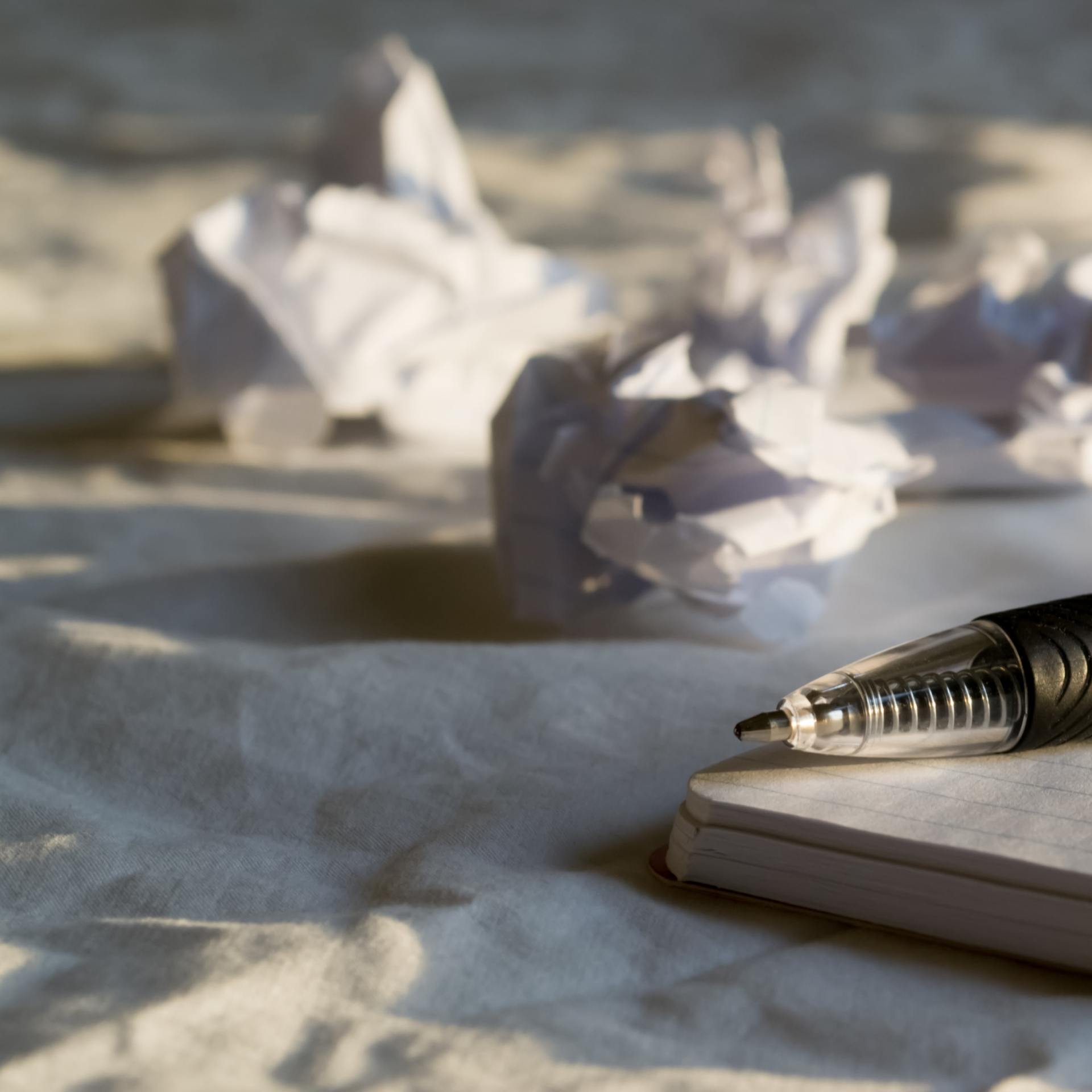 pen laying on a desk with crumpled papers