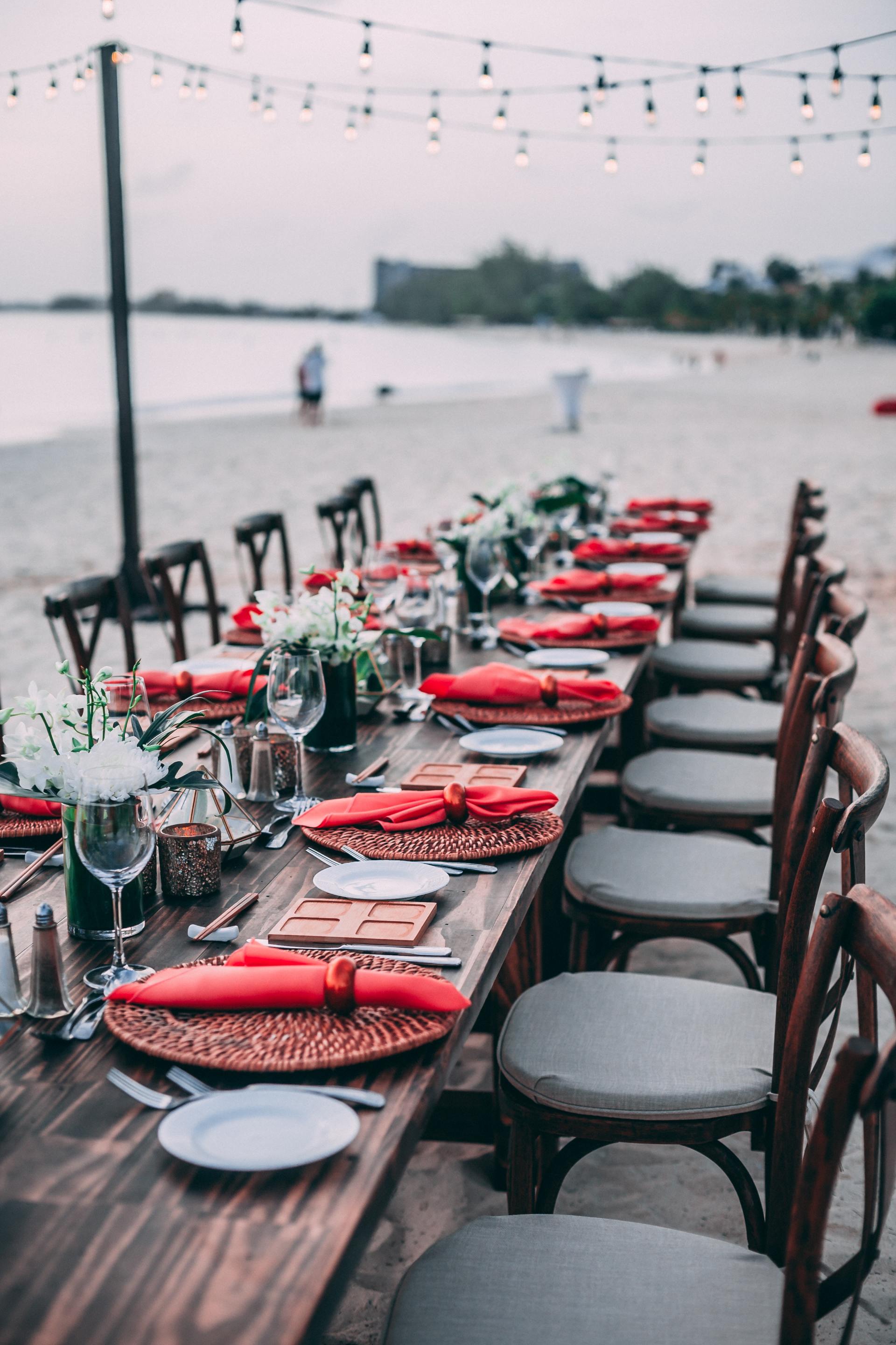 A well dressed table set for dinner on a beach at sunset