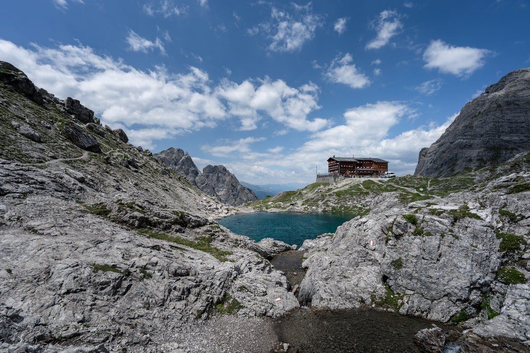 Ein kleiner See inmitten eines Berges mit einem Haus im Hintergrund