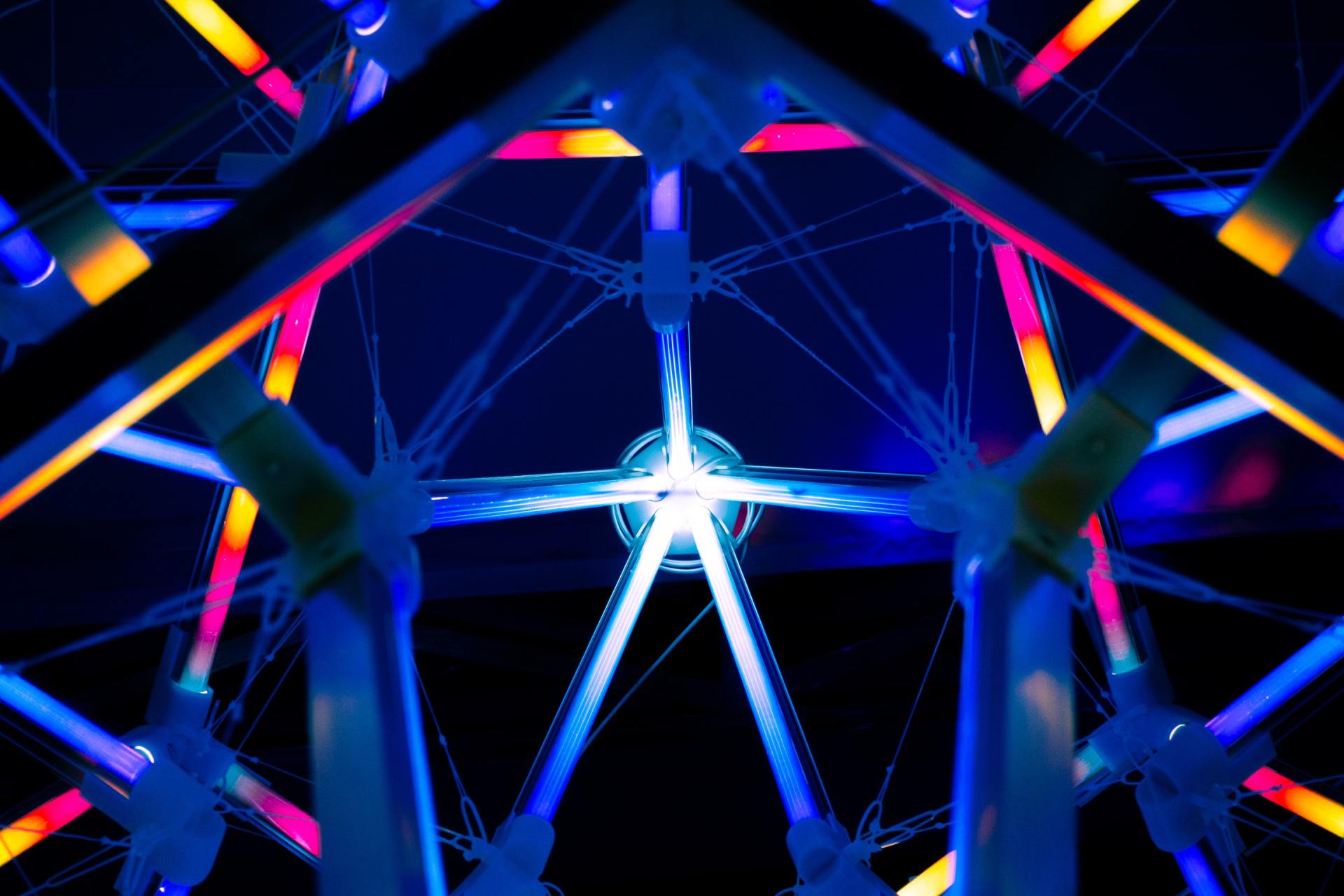 A ferris wheel is lit up at night and looks like a kaleidoscope