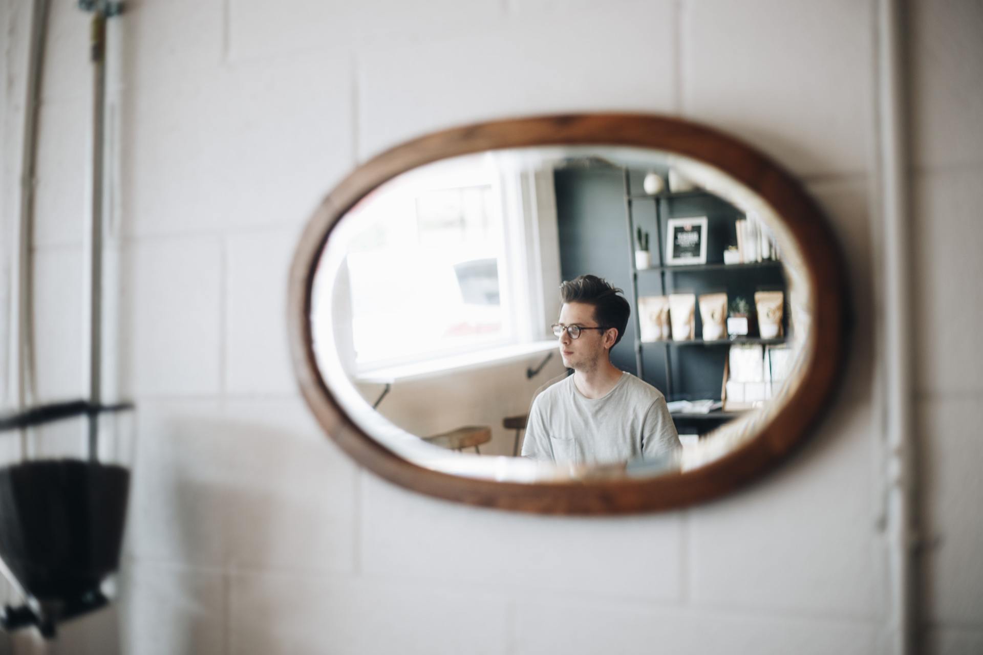 A man is sitting in front of a mirror looking at himself.