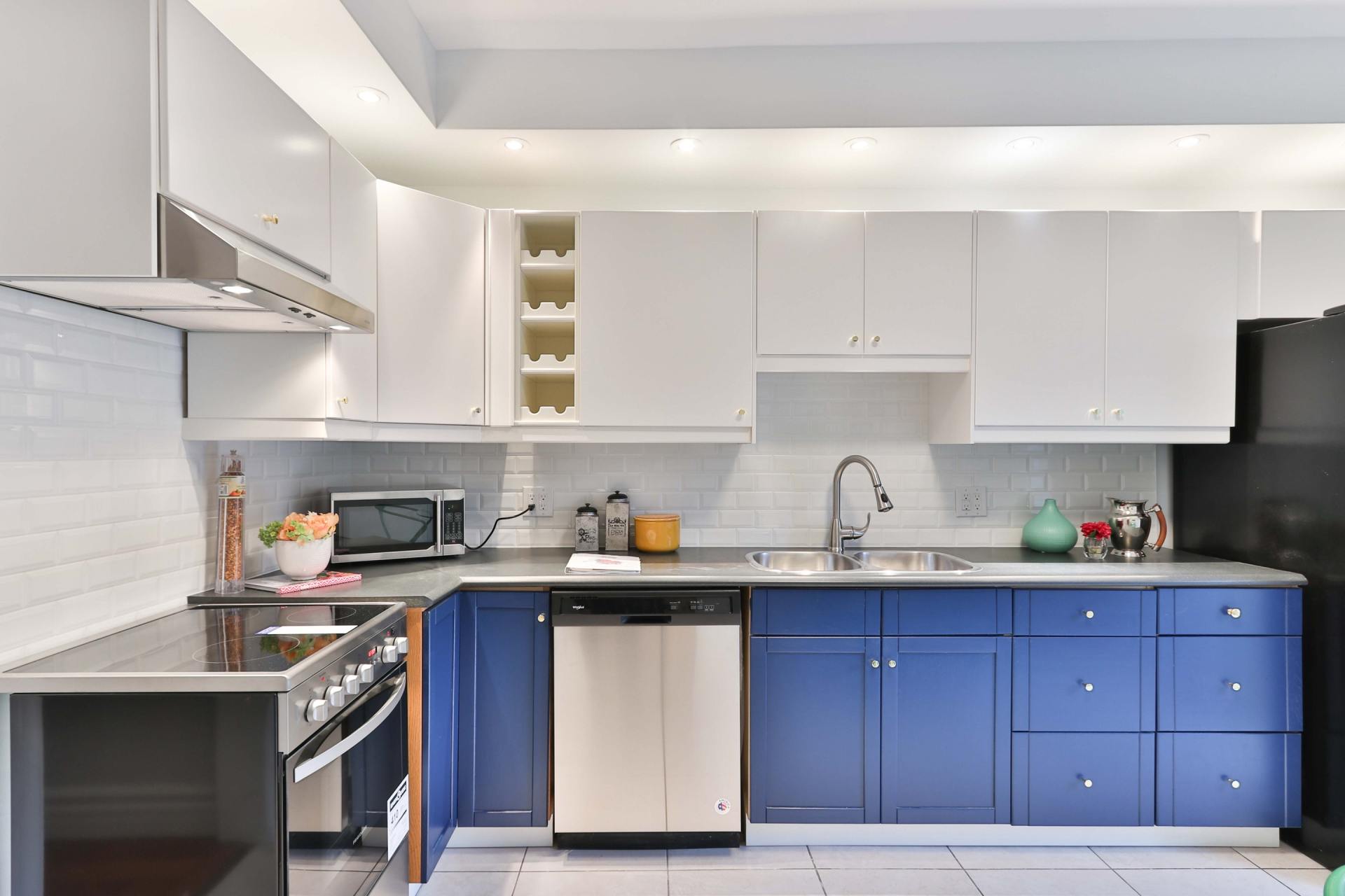 A kitchen with blue cabinets , white cabinets , and stainless steel appliances.