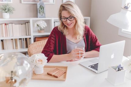 A woman is sitting at a desk using a laptop computer.