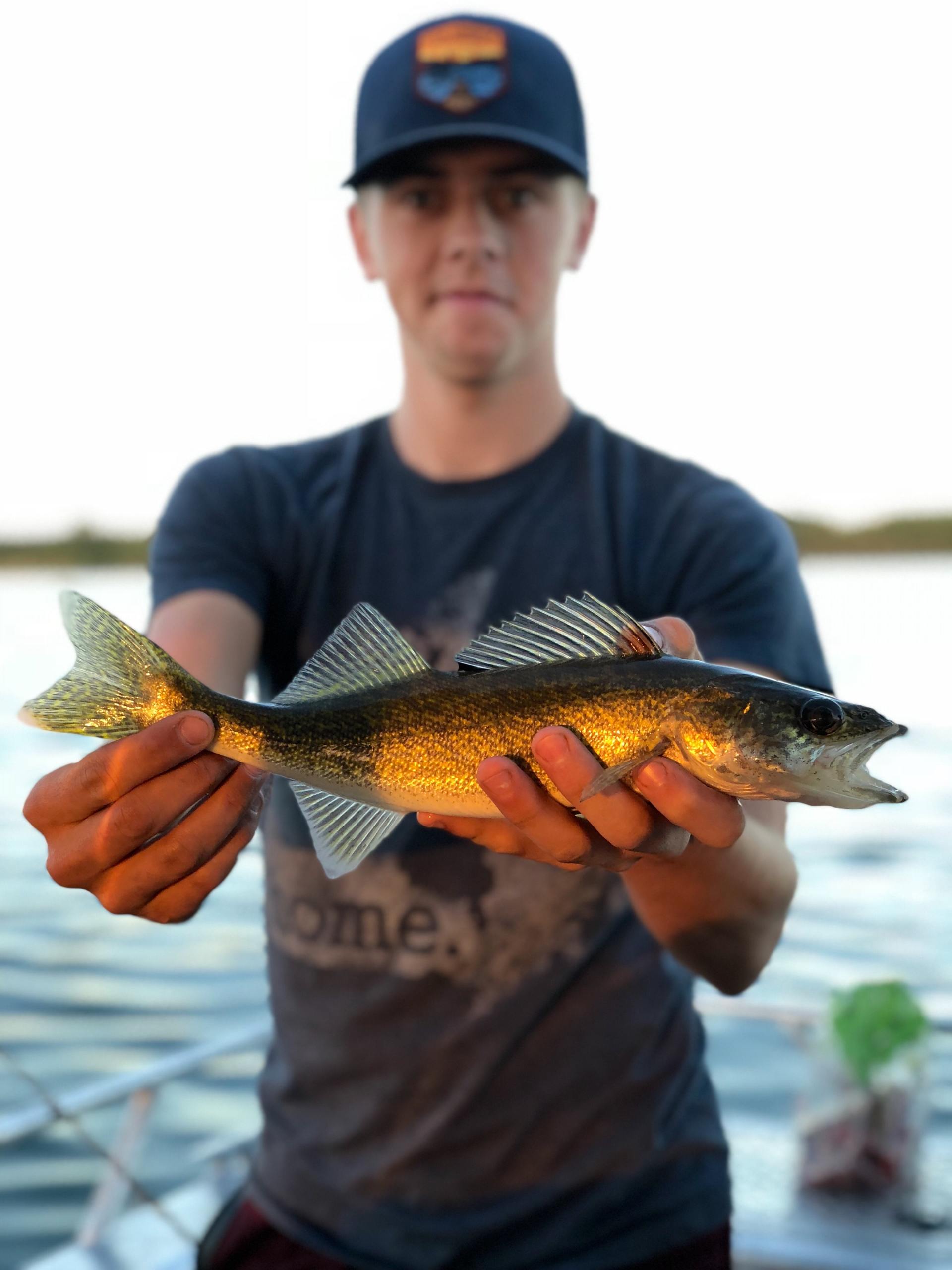 A man is holding a fish in his hands and his shirt says home