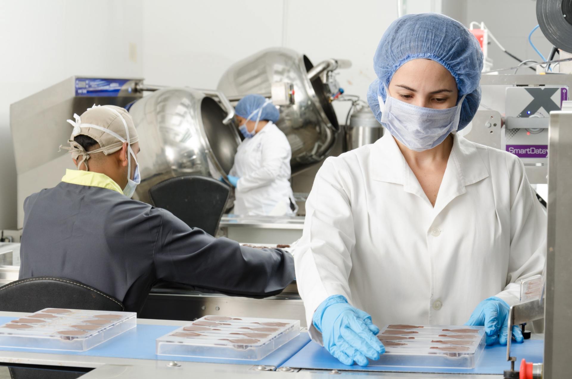 Eine Frau mit Maske und Handschuhen arbeitet in einer Fabrik