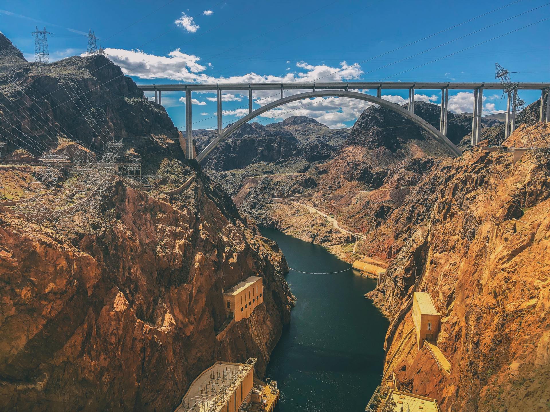 There is a bridge over a river in the middle of a canyon.