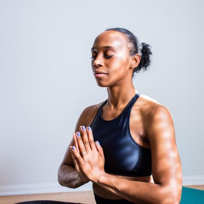 Woman in yoga pose, hands in prayer, eyes closed, athletic wear.