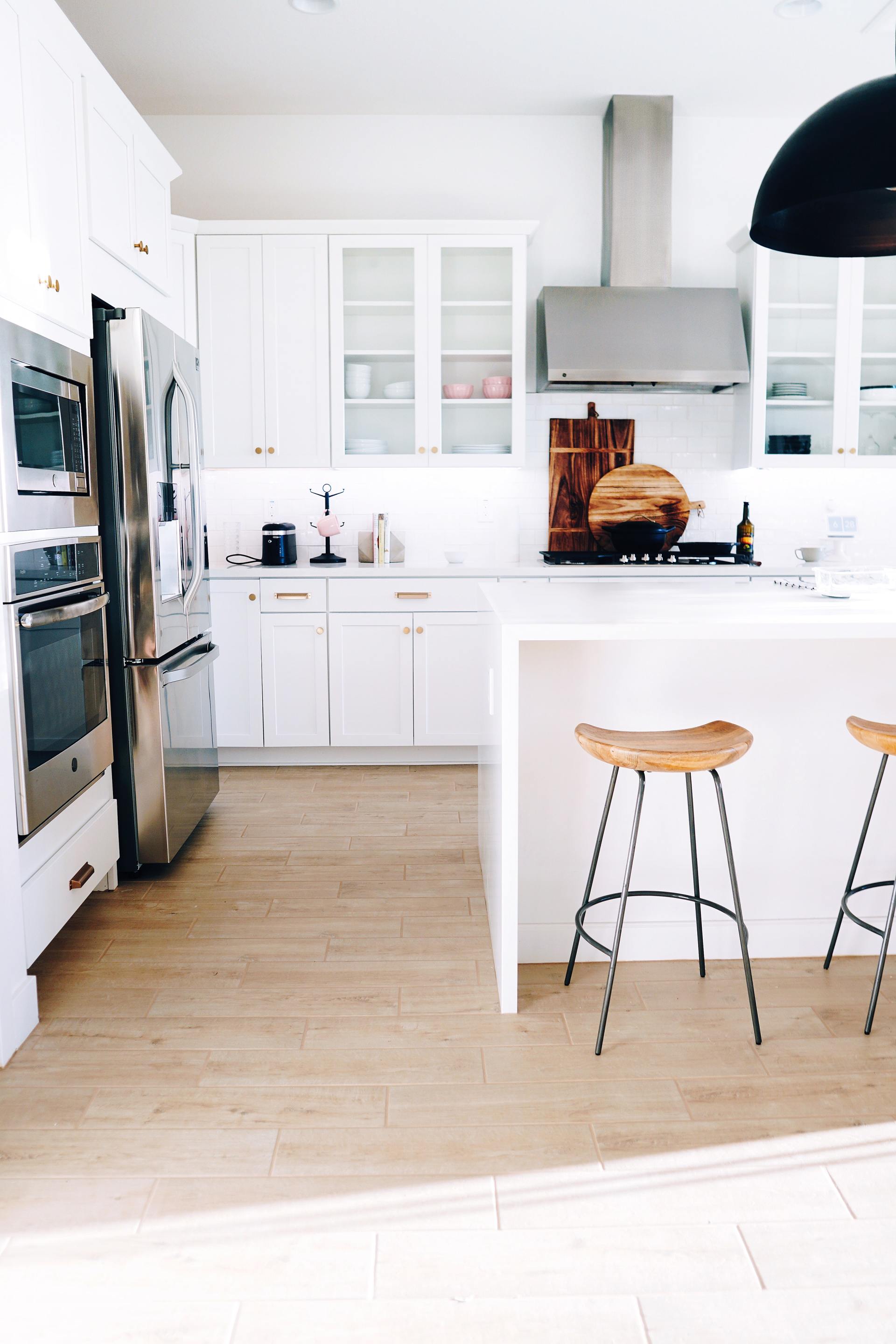 A kitchen with white cabinets , stainless steel appliances , and wooden floors.