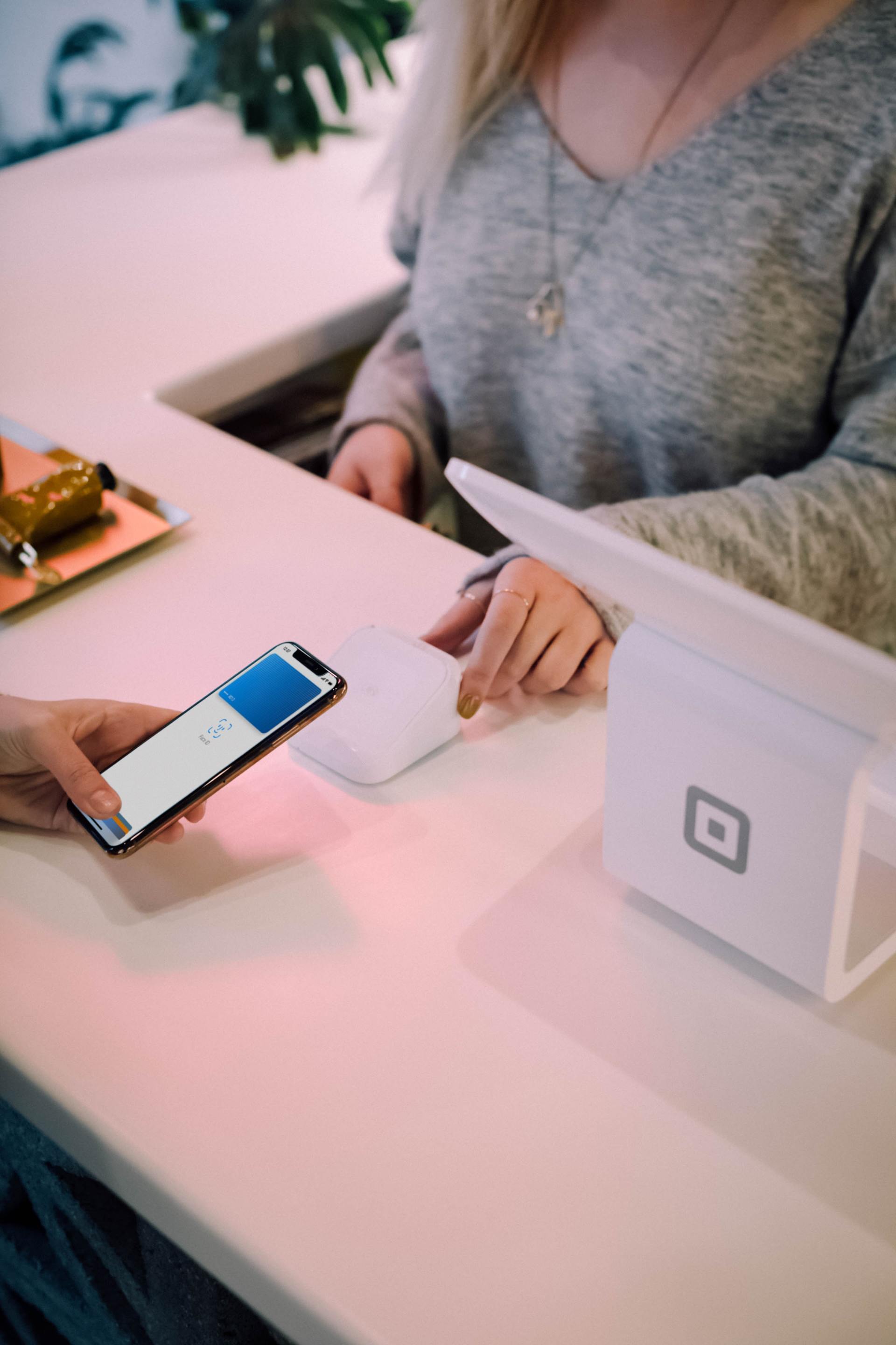 An up close photo of an in-store transaction, as the buyer holds phone over electronic chip reader.