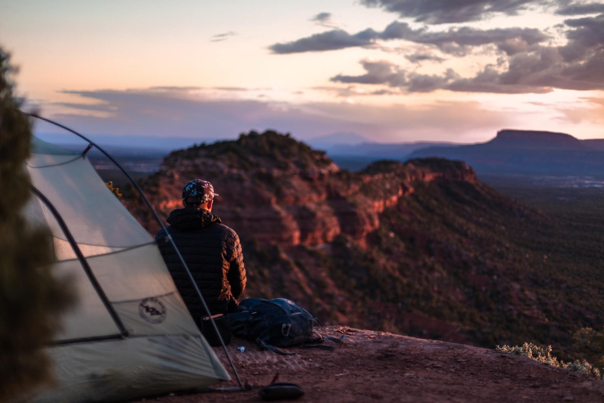 A man is sitting in a tent on top of a mountain.