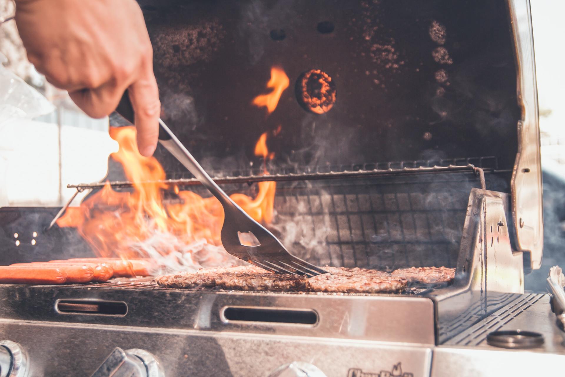 A person is cooking food on a grill with a spatula.