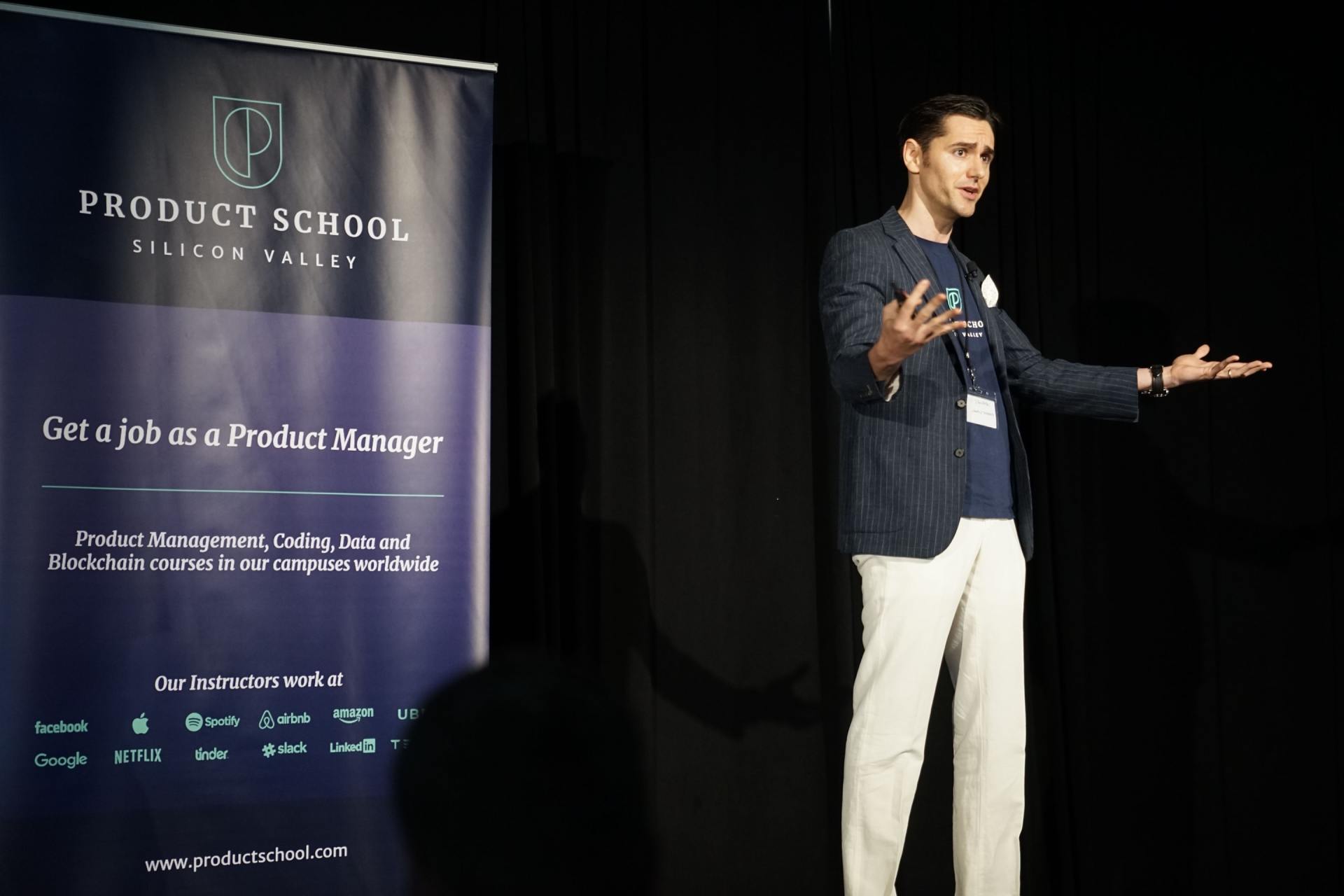 A man is giving a presentation in front of a product school sign.