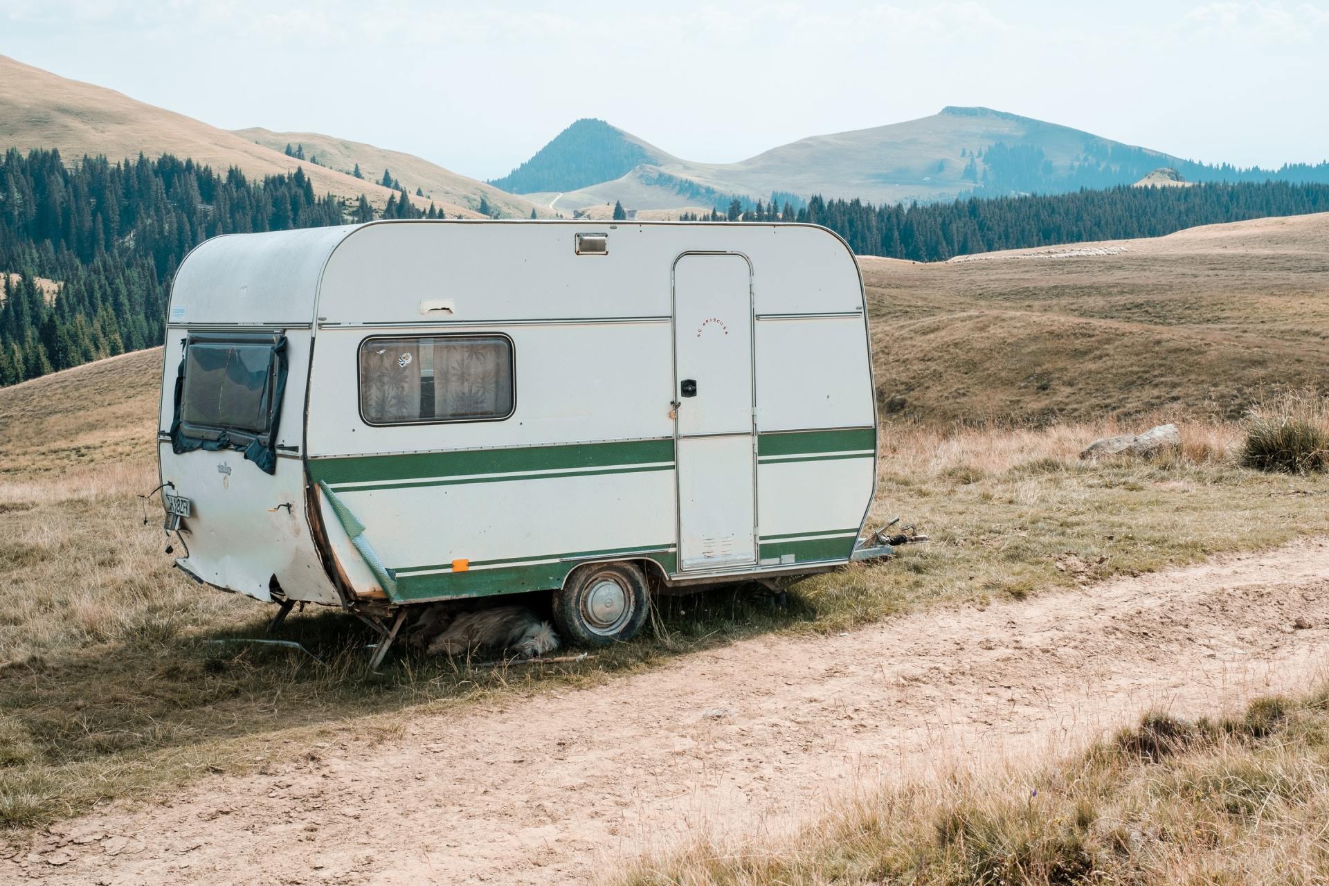 A green & white 5th wheeler infront of the scenic mountain side