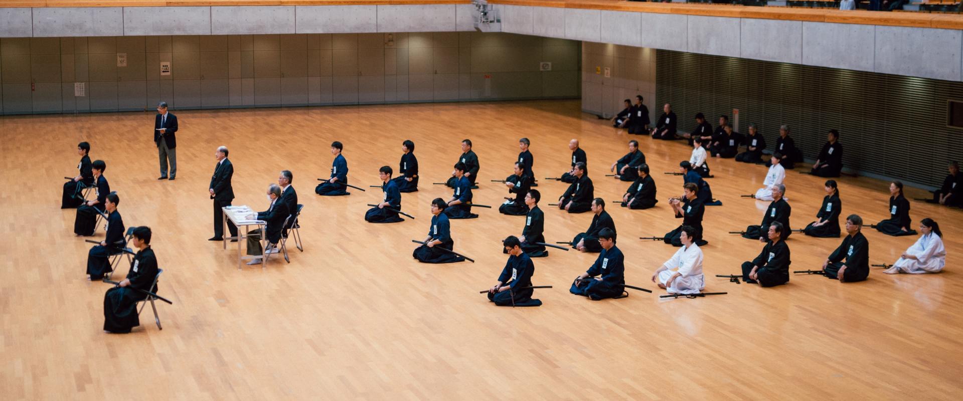 A group of people are sitting on the floor in a gym.