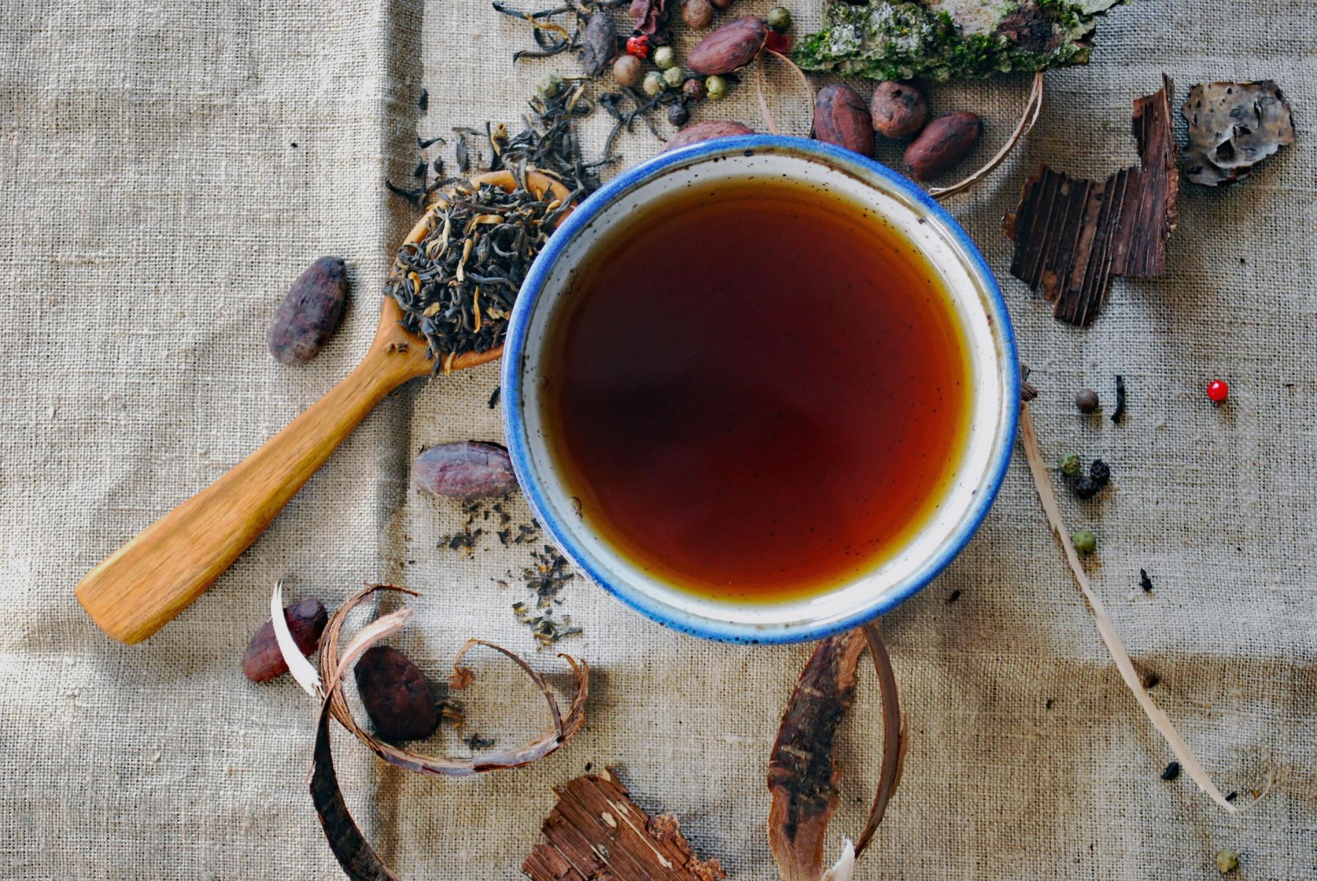 A cup of tea is sitting on a table next to a wooden spoon.