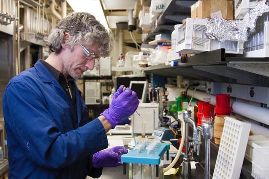 A man wearing purple gloves is working in a lab