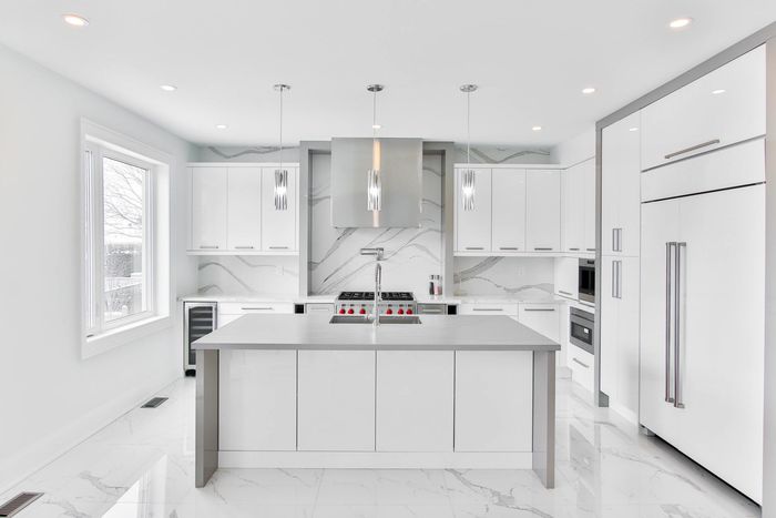 A kitchen with white cabinets and a large top in the middle.