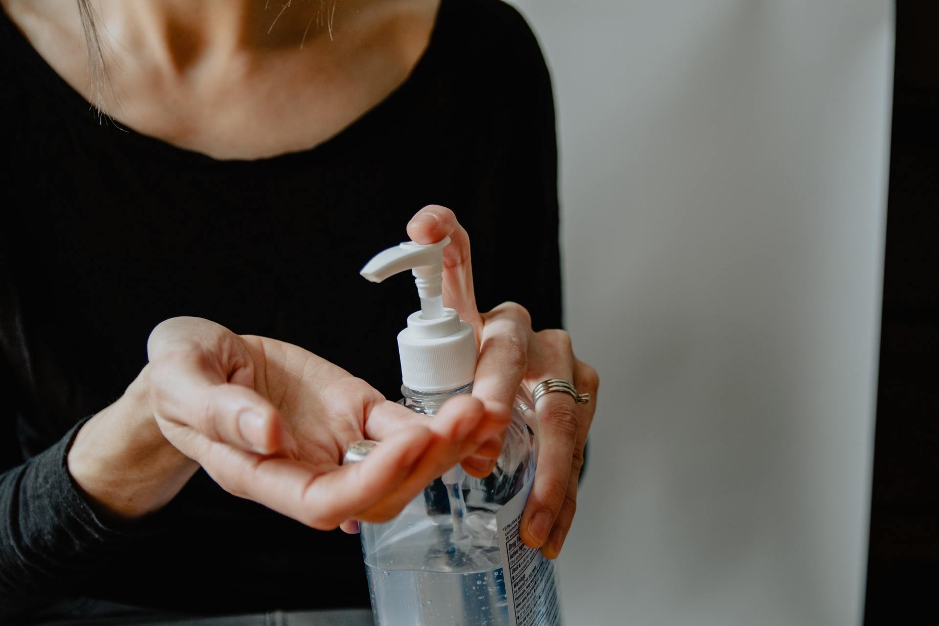 A woman is holding a bottle of hand sanitizer in her hand.