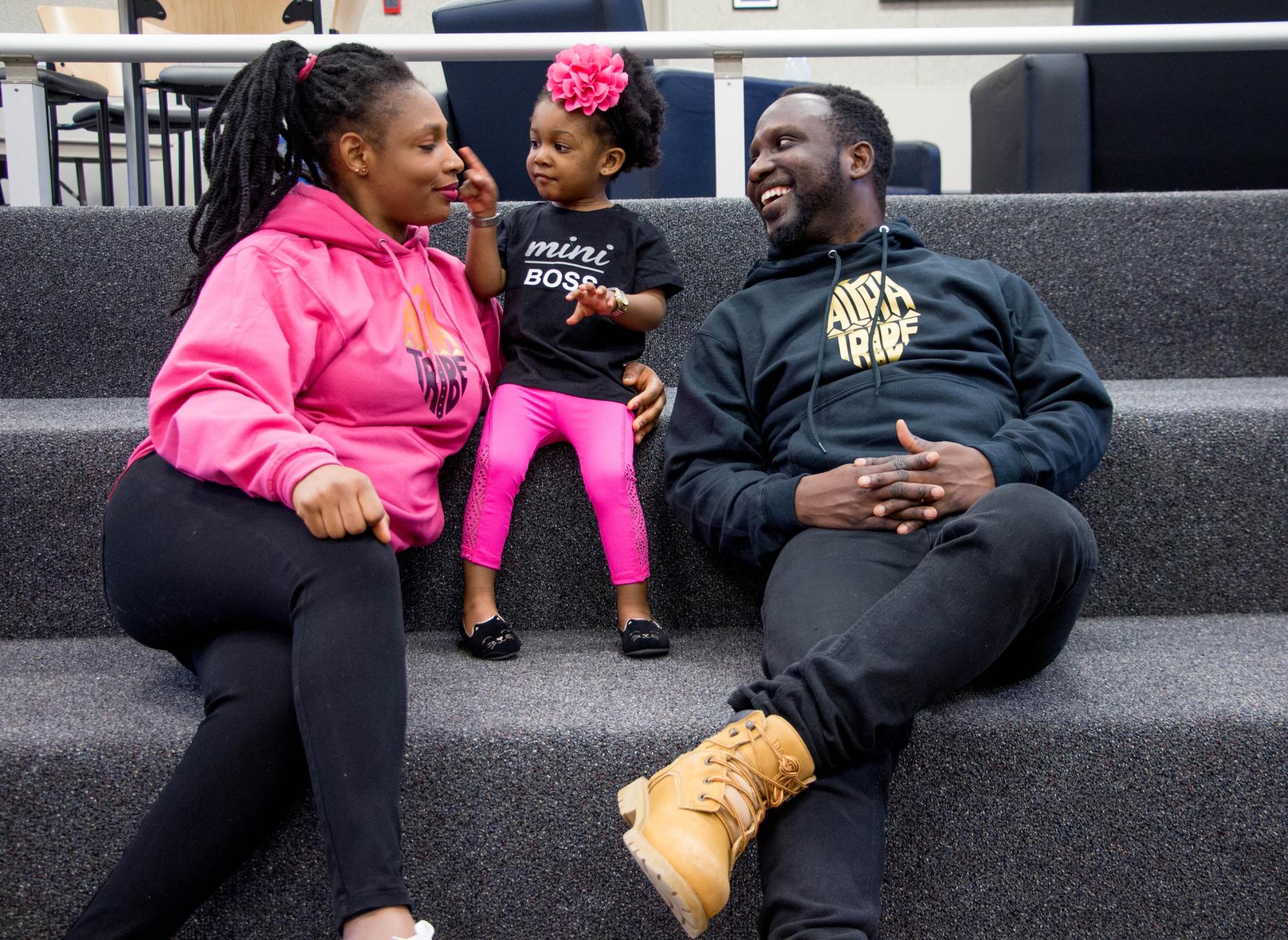 Two African American parents playing with their young child