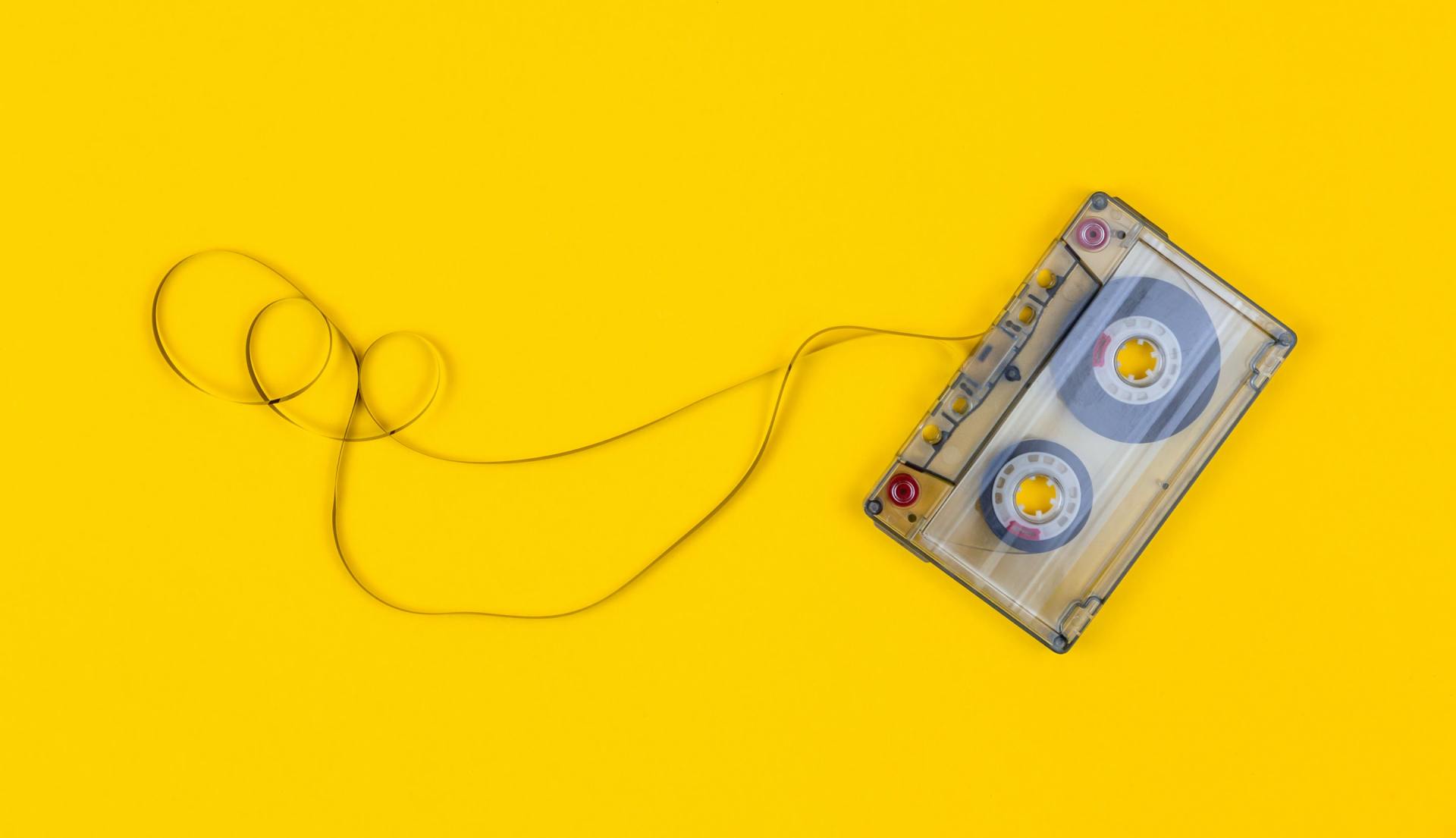 A close up of a cassette tape on a yellow background.