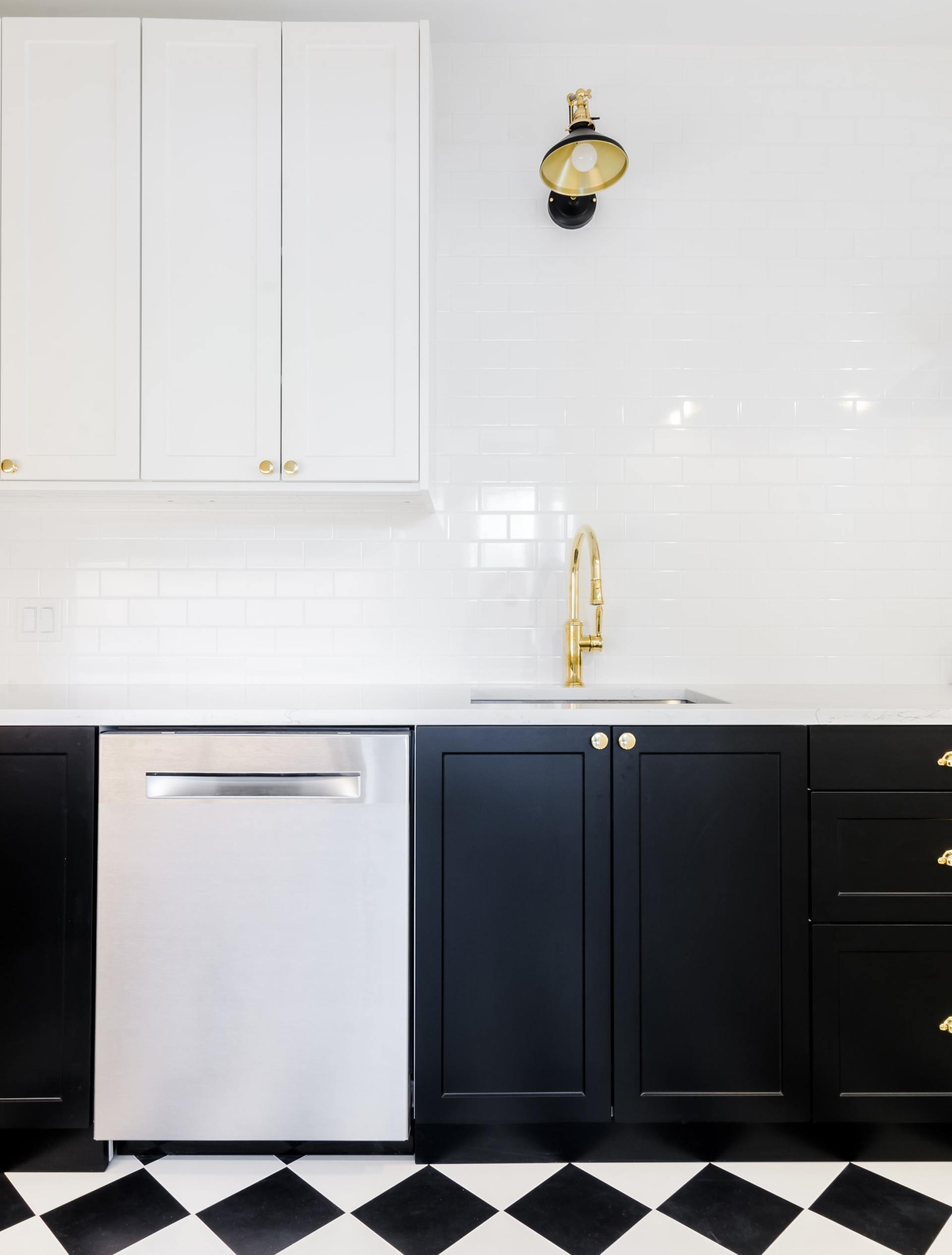 A kitchen with black and white cabinets and a checkered floor