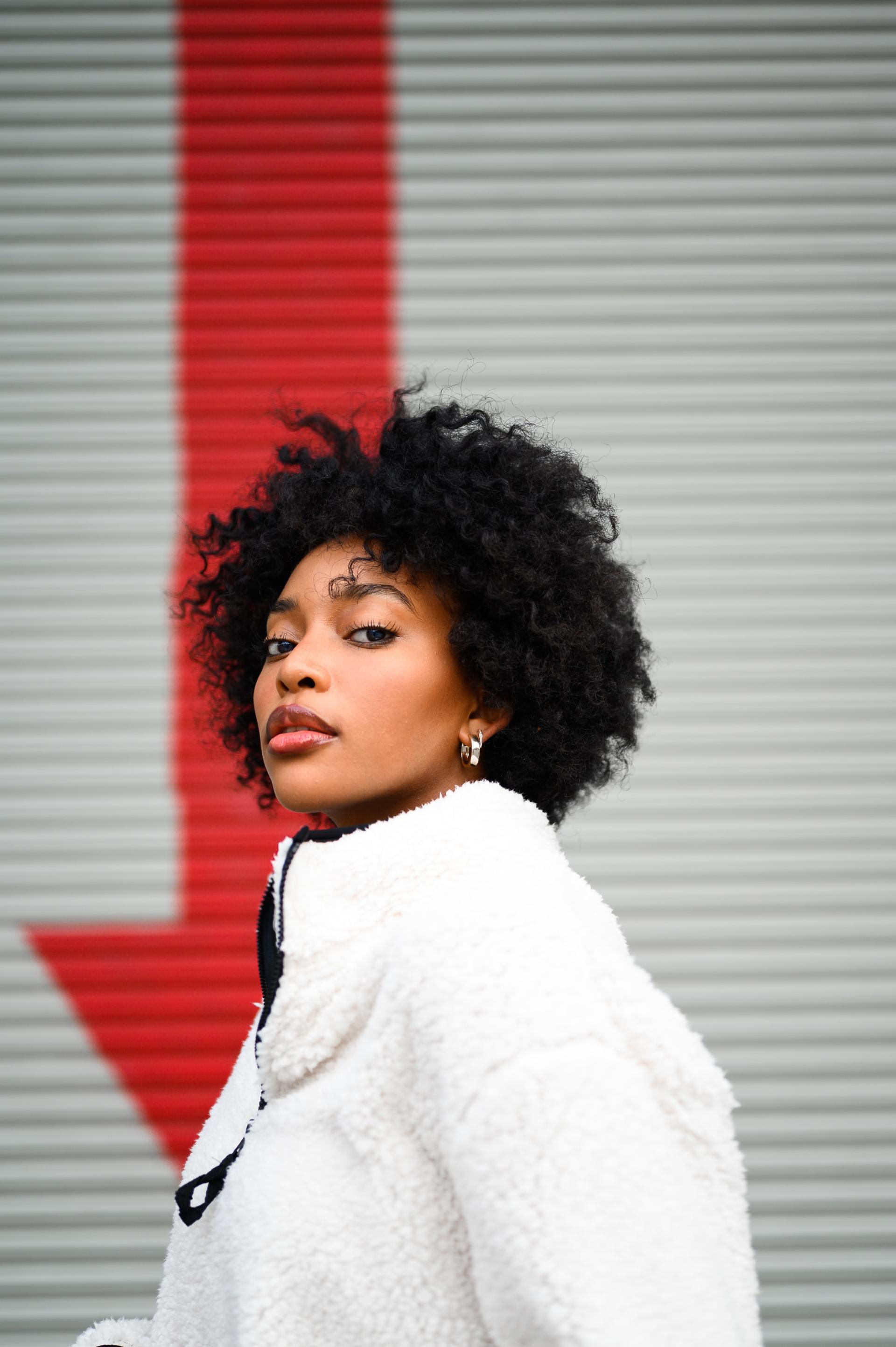 A woman in a white coat is standing in front of a red arrow.