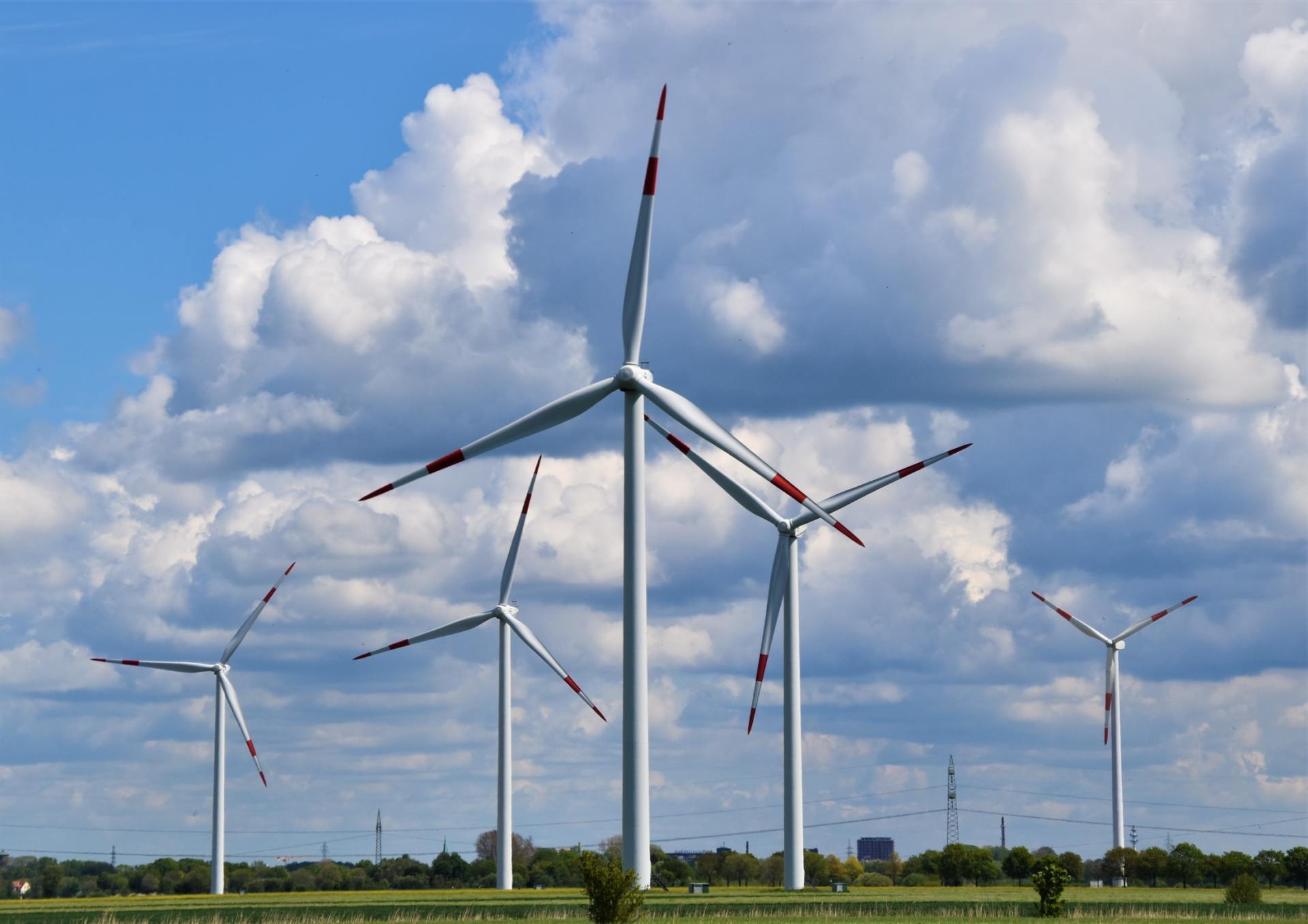 Wind turbines in a grassy field under a cloudy blue sky