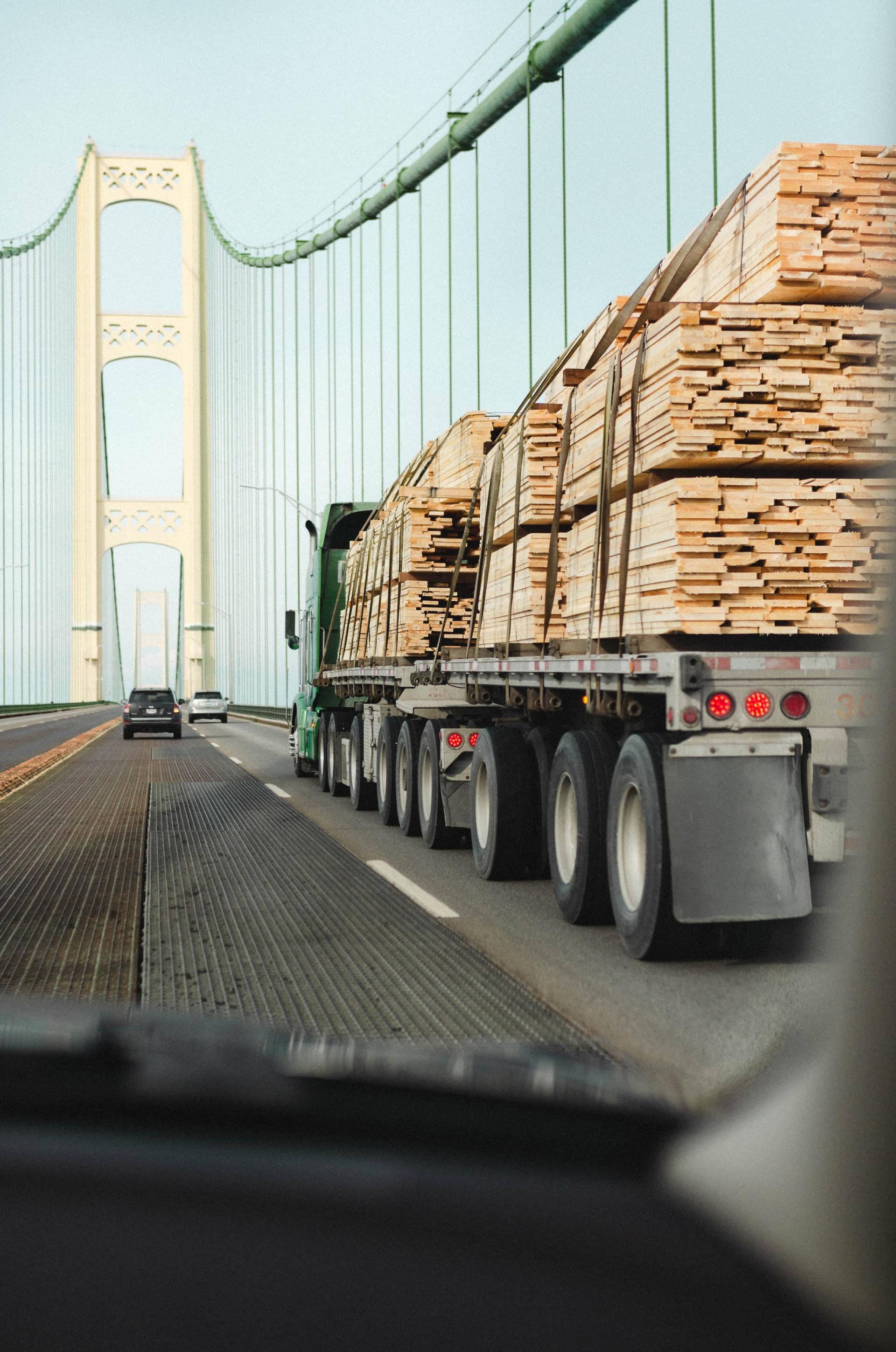 A truck is driving down a highway with a bridge in the background.