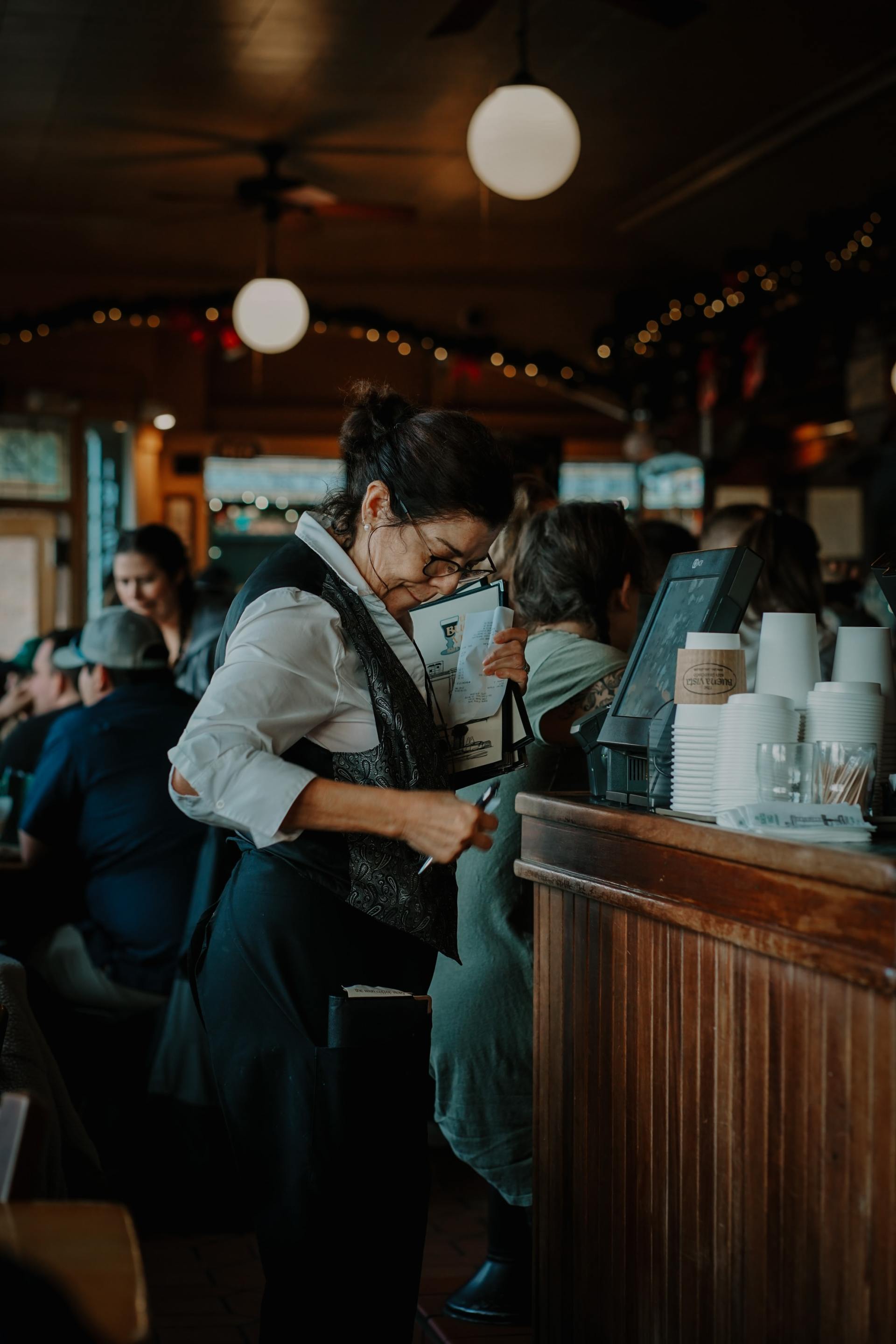 A woman is standing at a counter in a restaurant.