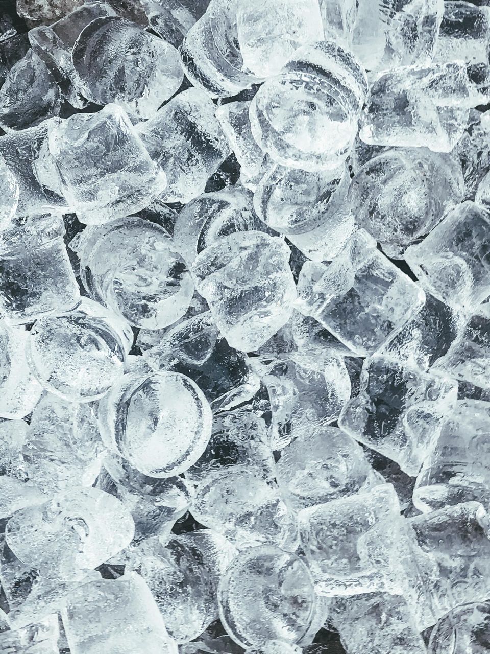 Primo piano di cubetti di ghiaccio trasparenti impilati uno sull'altro, scintillanti di brina.