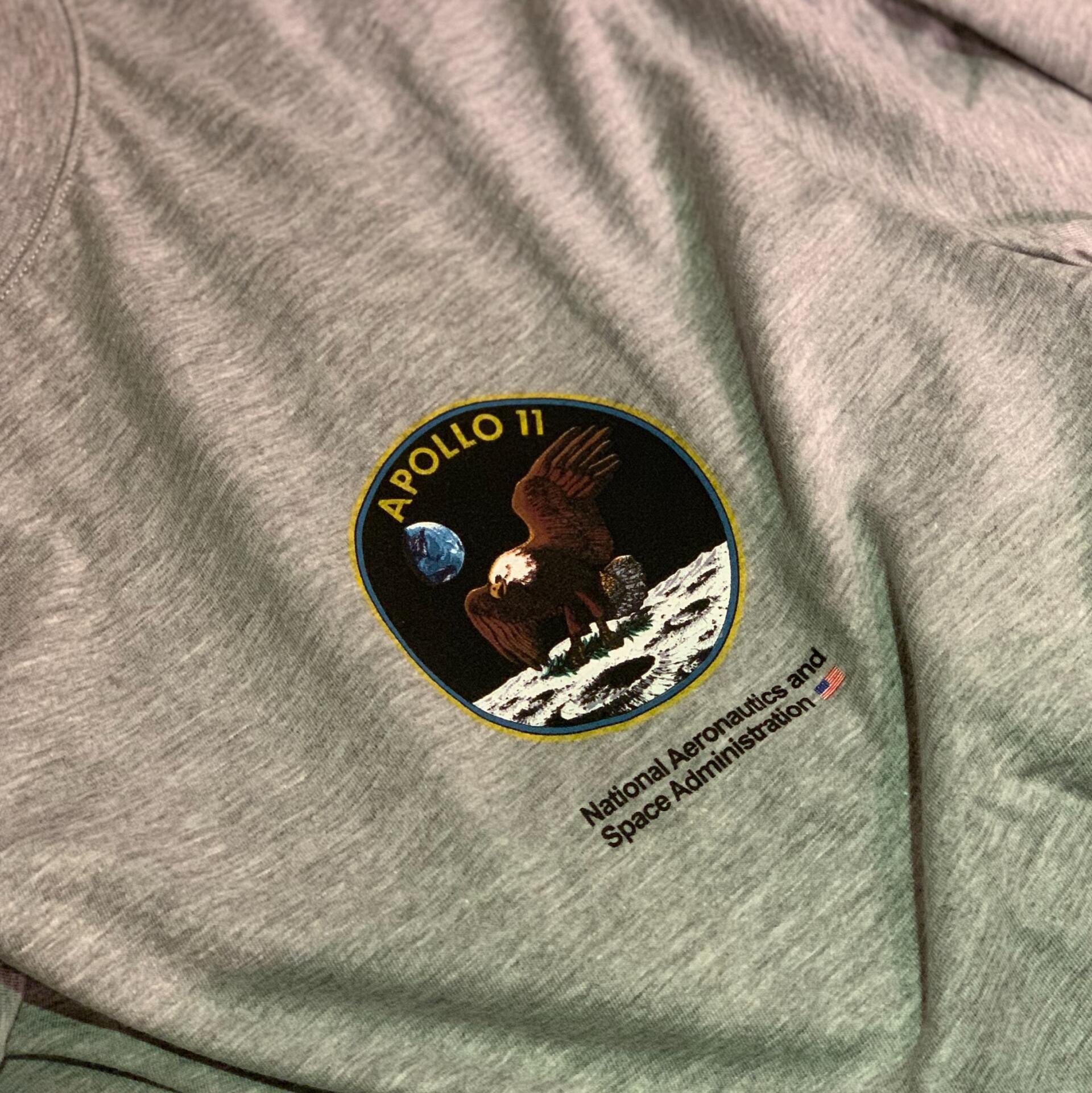 Gray T-shirt with an Apollo 11 lunar landing patch on the chest