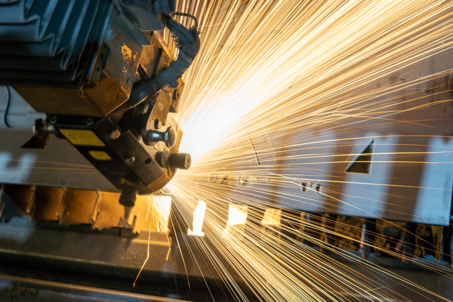 Laser cutting metal, sparks flying in an industrial setting.