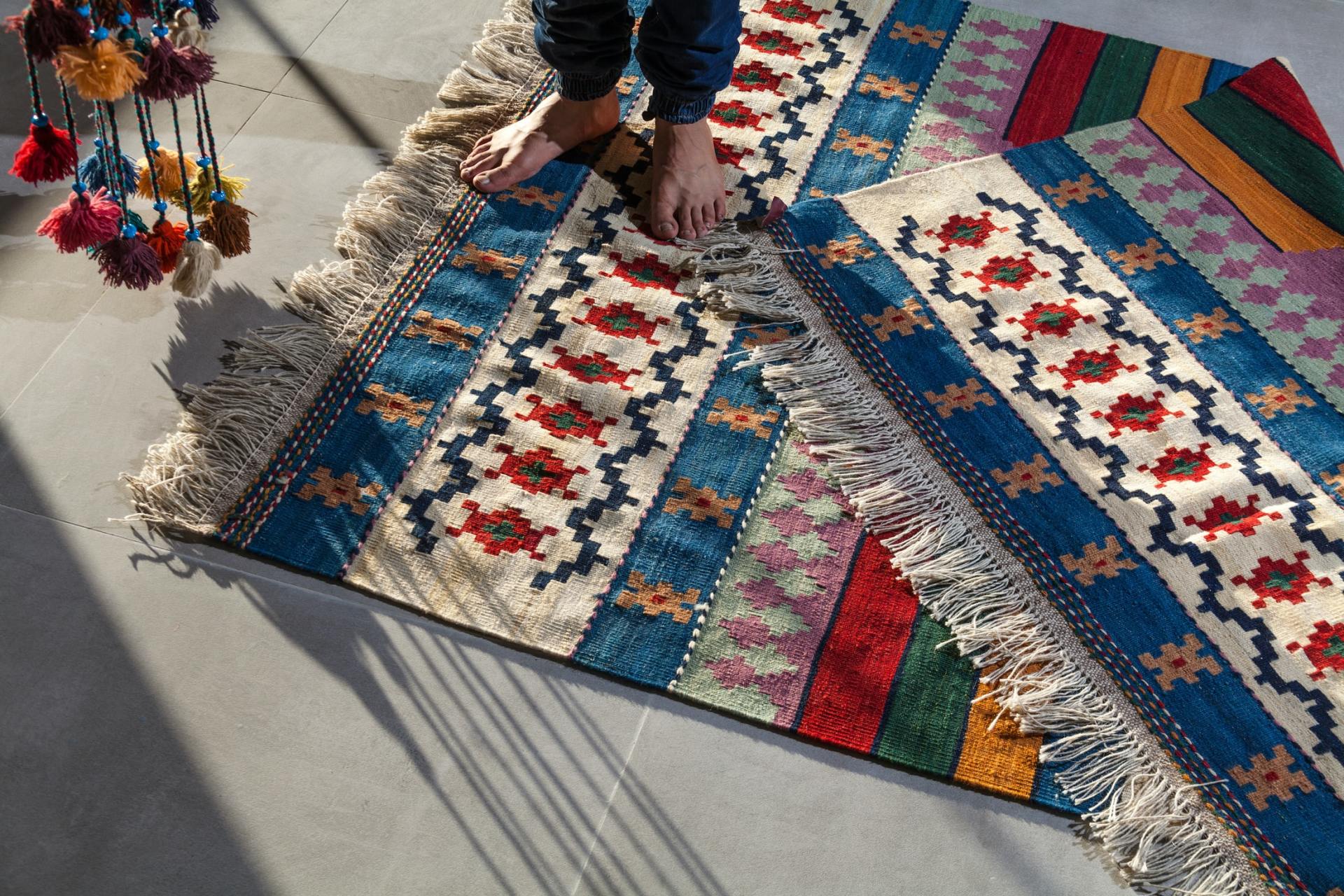 Bare feet on patterned rugs; blue, red, and cream geometric design.