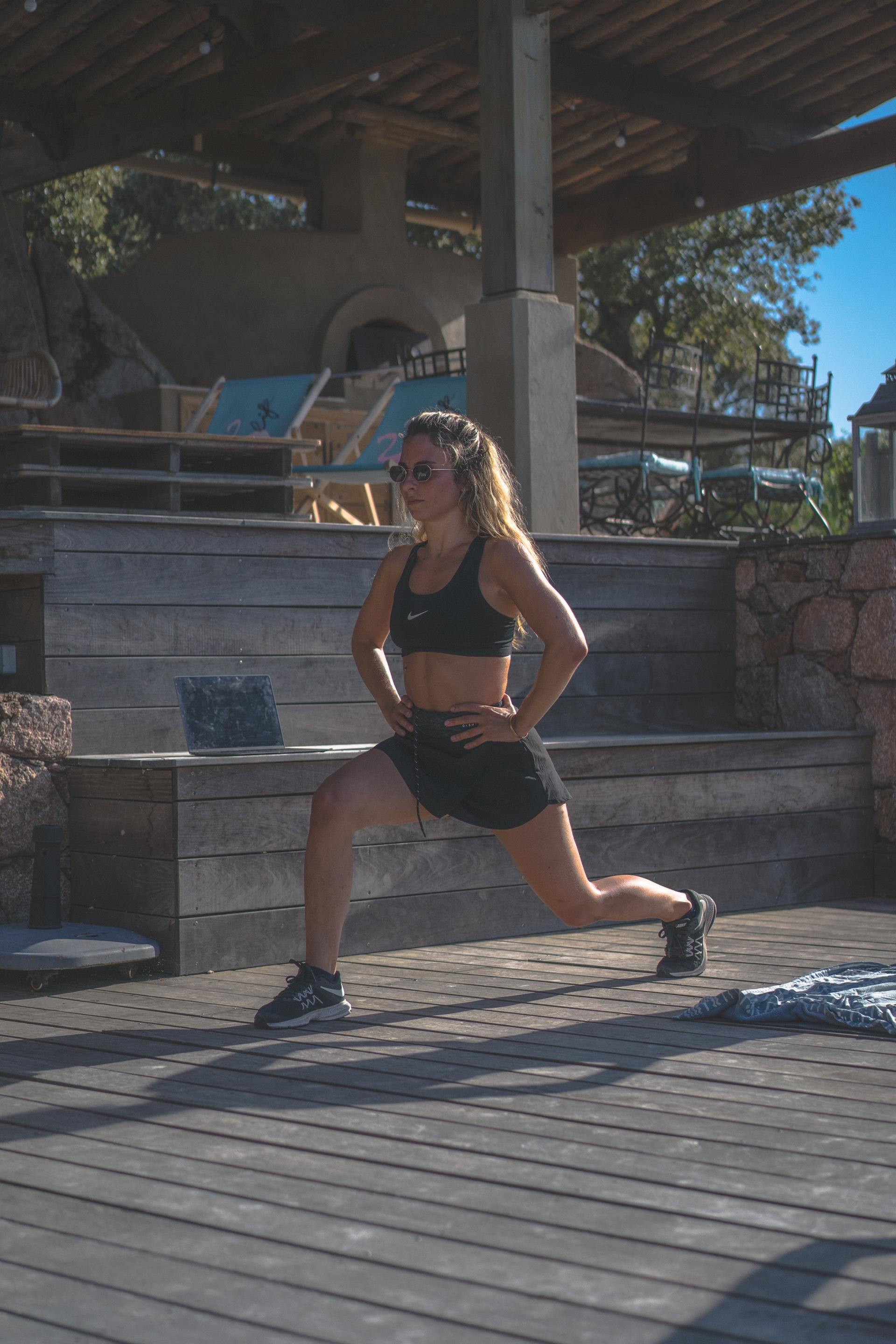 A woman is stretching her legs on a wooden deck.