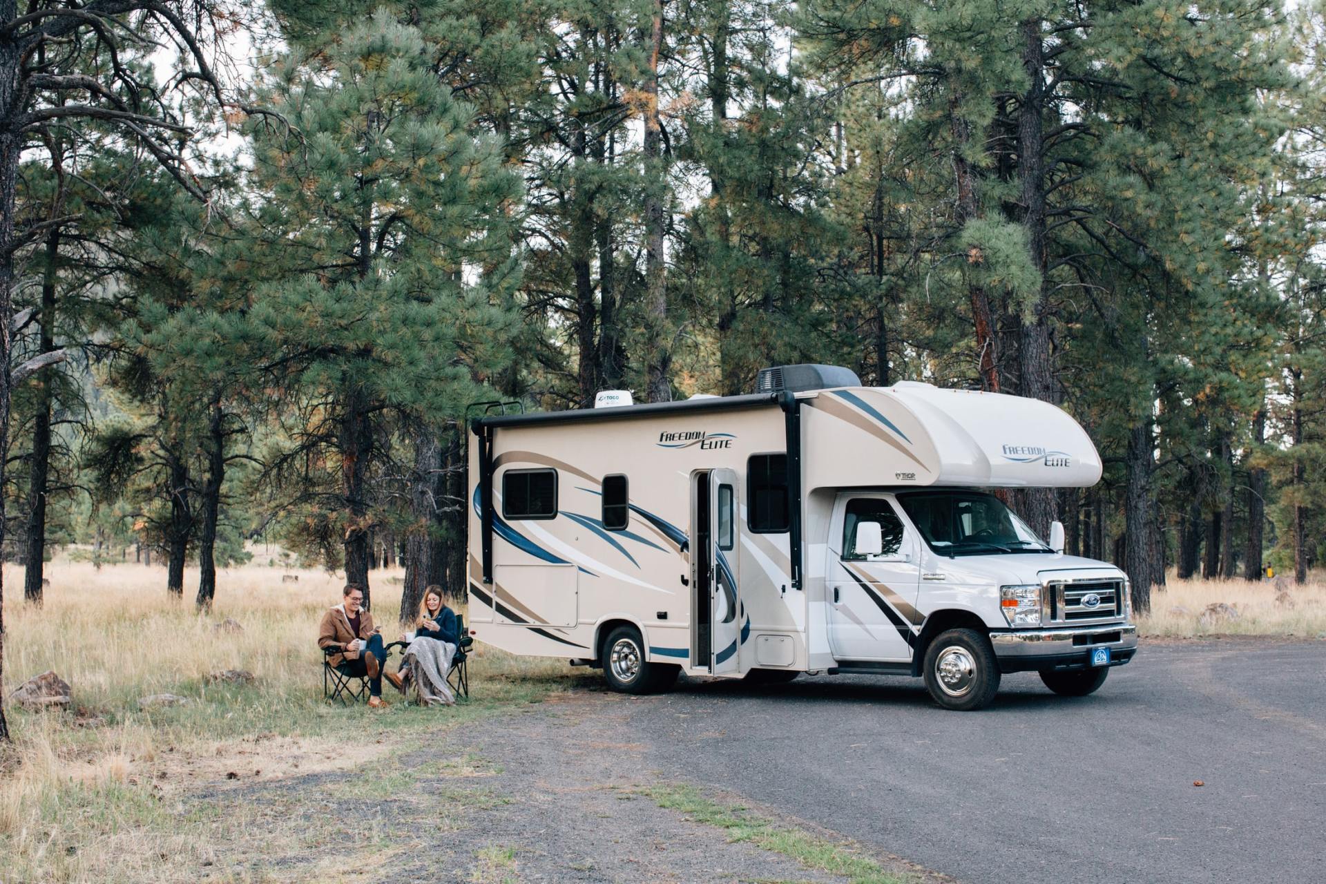 A couple sitting on camp chair enjoying the wilderness next their RV