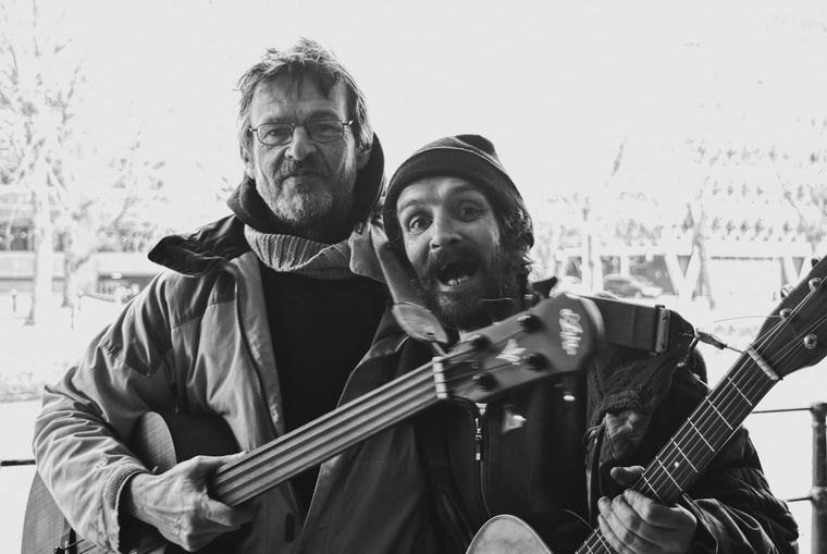 Two men are playing guitars in a black and white photo.