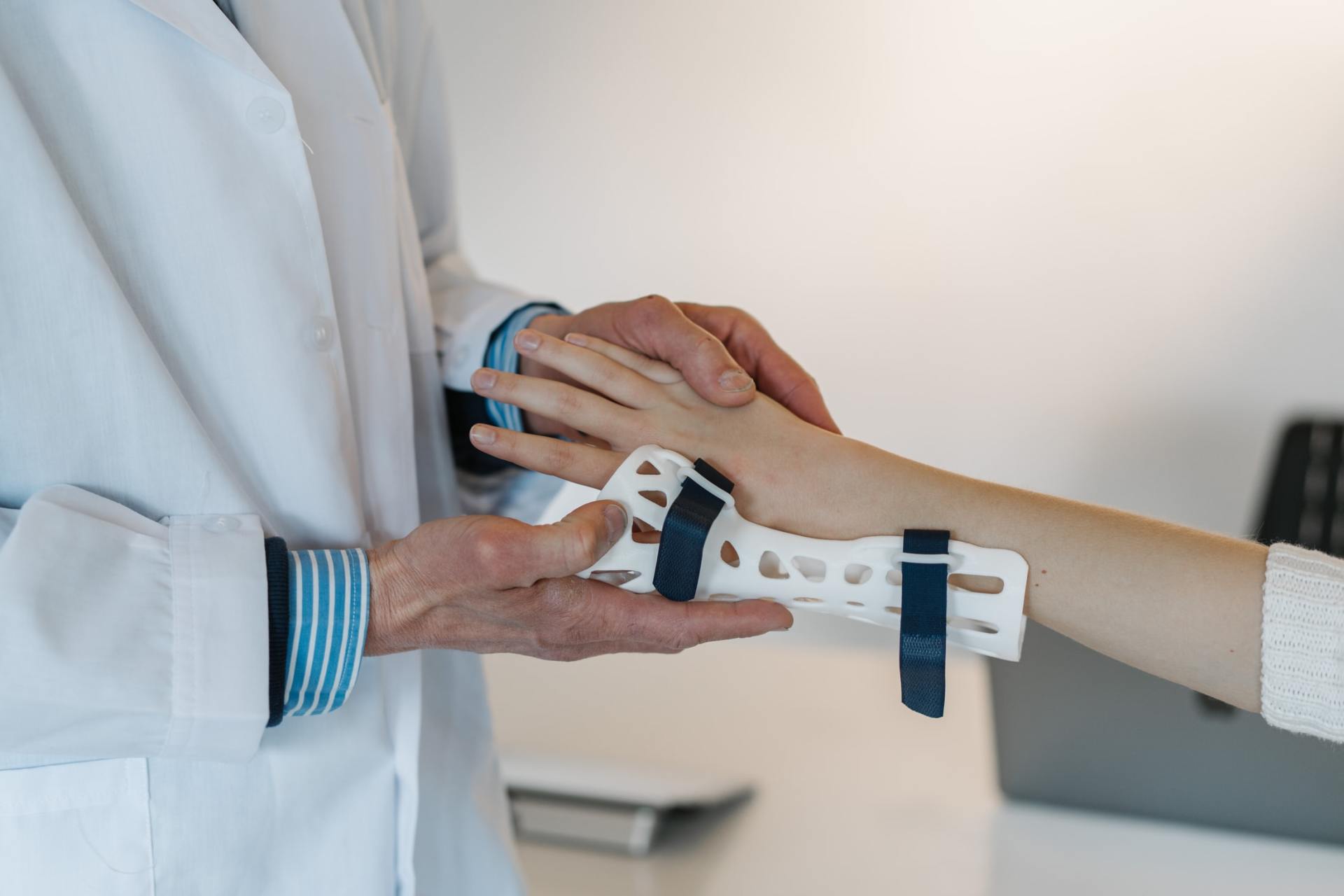 Ein Arzt hält die Hand eines Kindes mit einem Gipsverband.