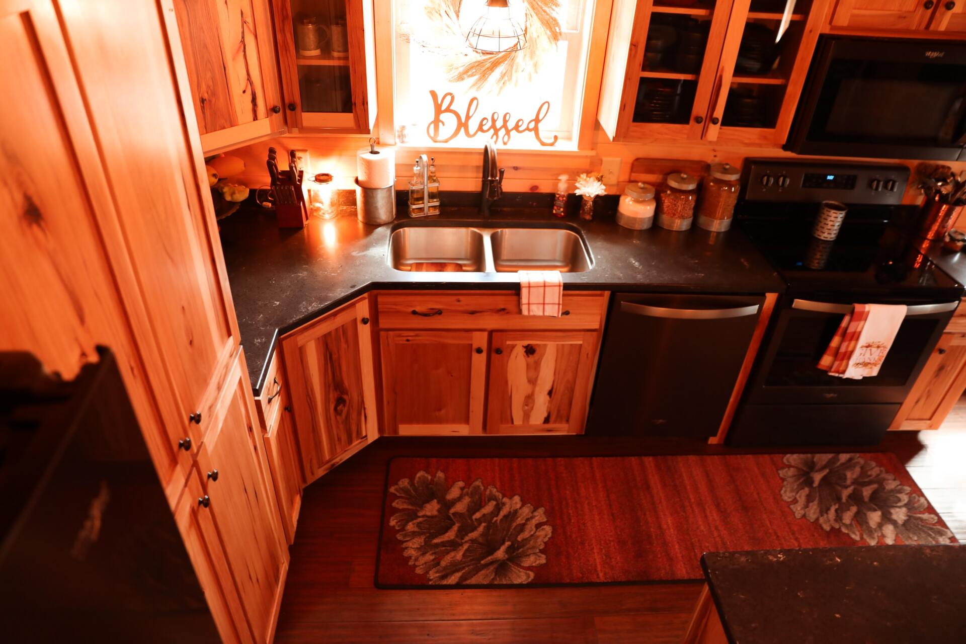Kitchen with wooden cabinets, black countertops, stainless steel sink, and appliances. A 