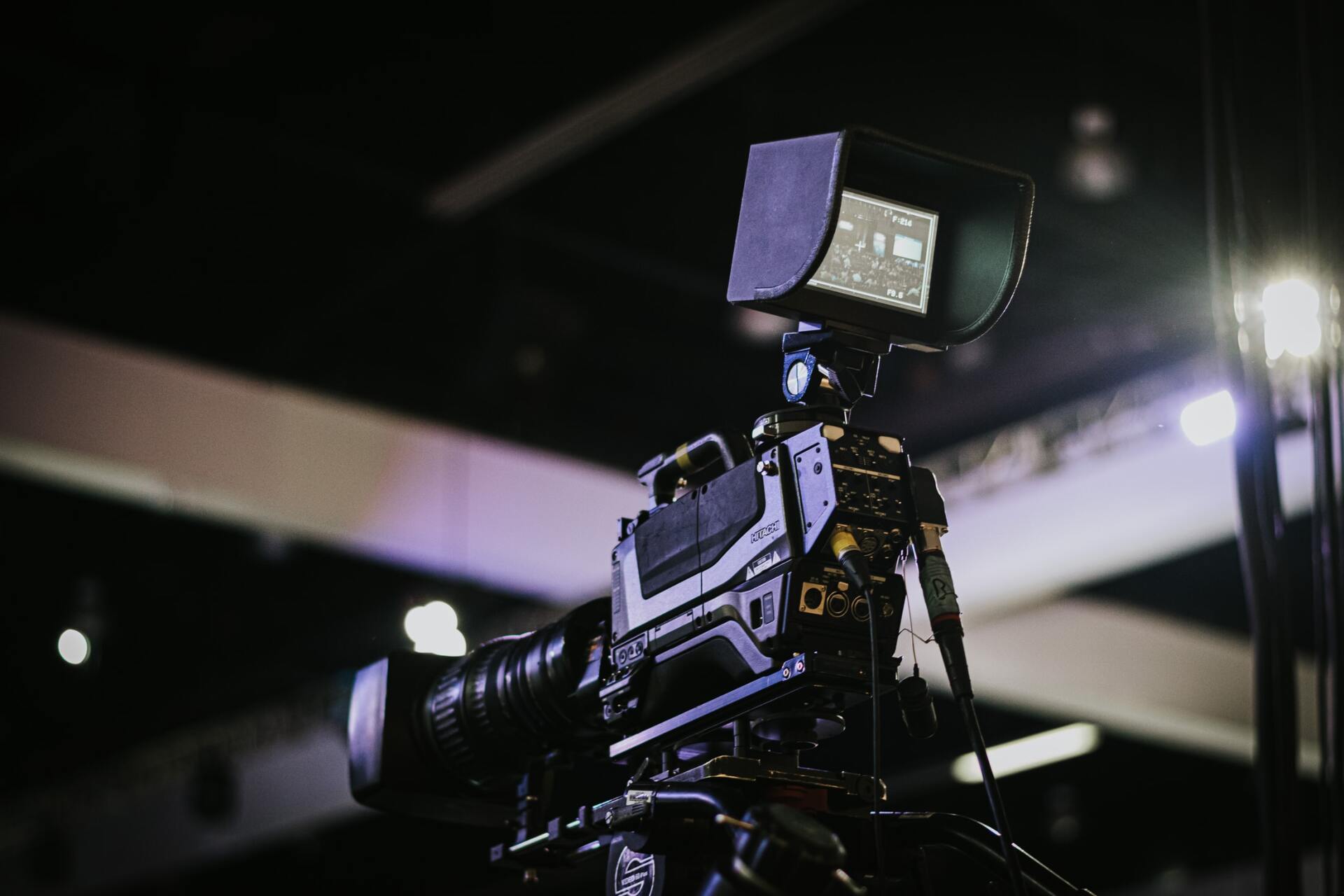 A video camera is sitting on a tripod in a dark room.