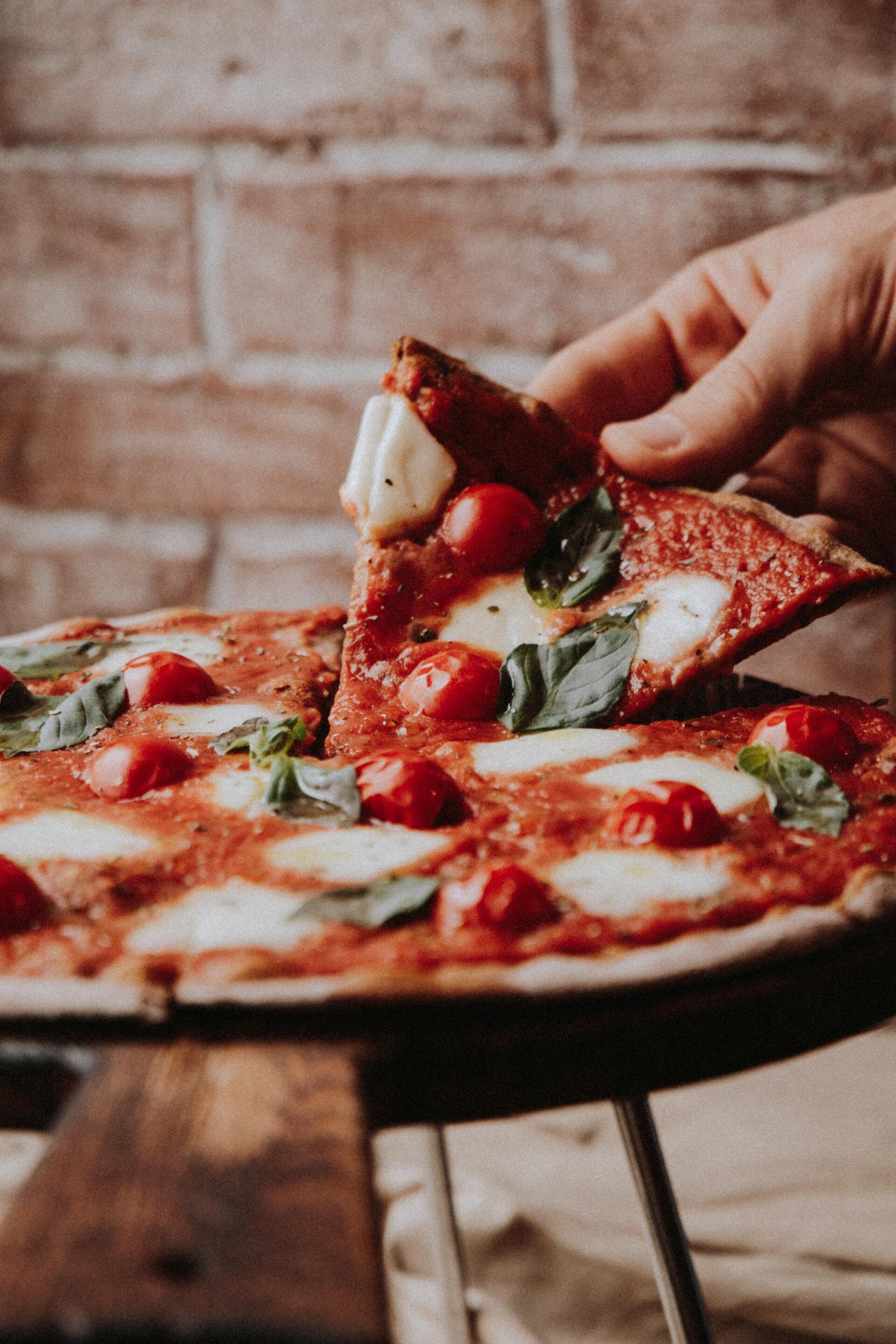 A person is taking a slice of pizza from a pizza pan.