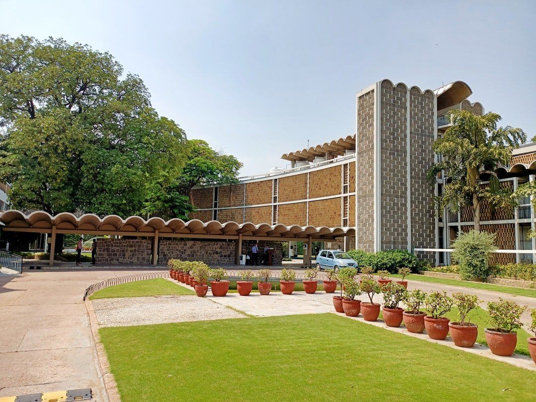 Exterior of a modern building with a textured facade, trees, and a grassy area.