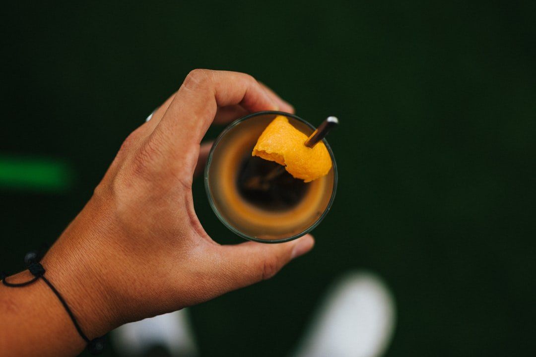 Een persoon houdt een glas vast met daarin een schijf ananas.