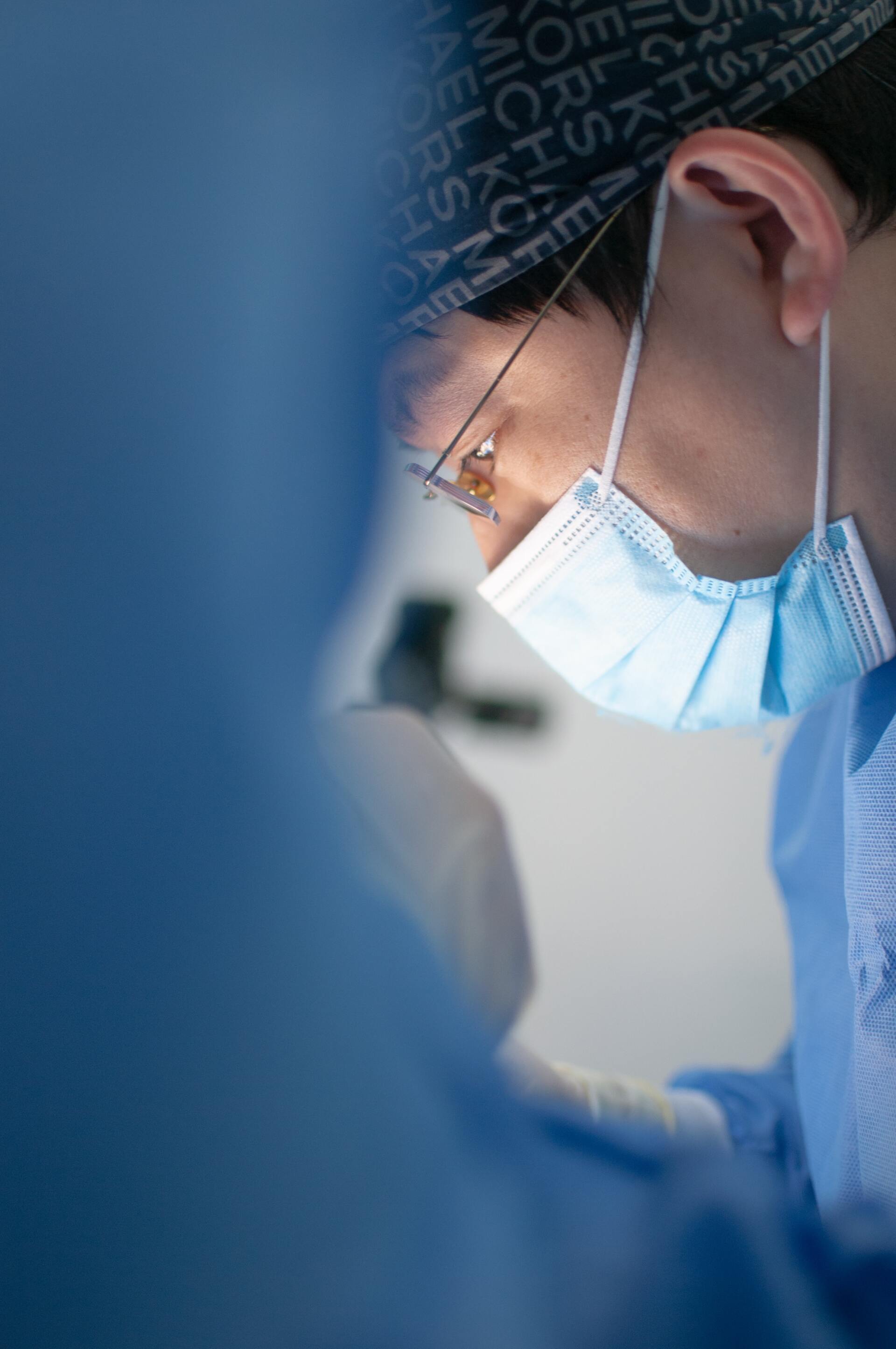 Surgeon in blue scrubs and mask, focused in an operating room